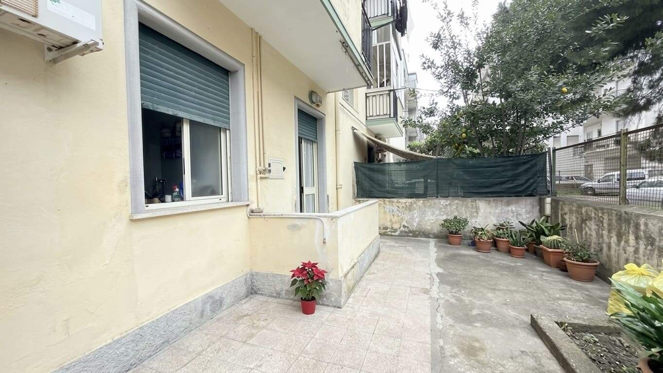 Ampio balcone con piante in vaso e tende da sole, ideale per relax e socializzazione in zona residenziale tranquilla.