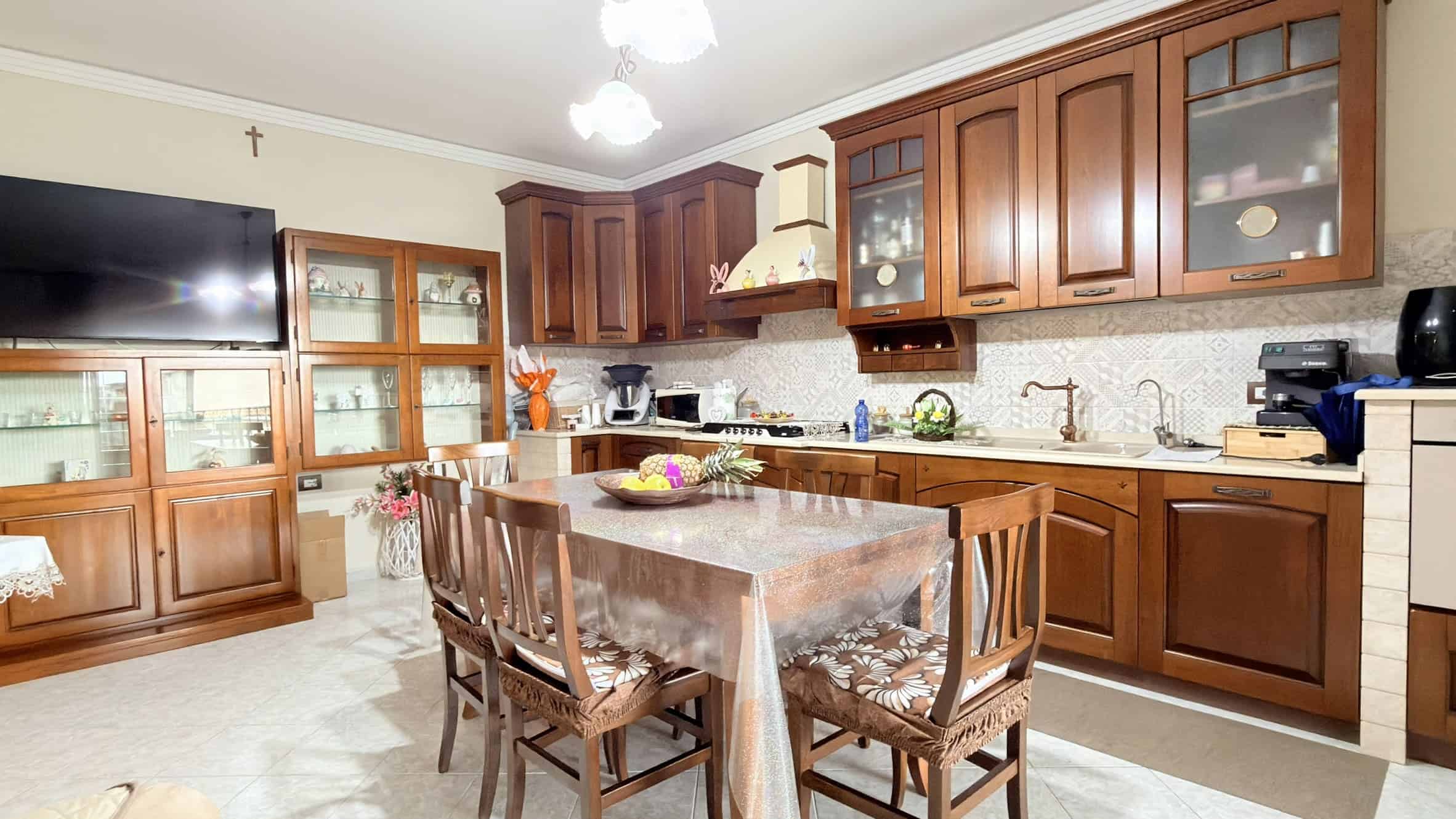 Piano cucina in legno con isola centrale, elettrodomestici moderni e spazio funzionale, ideale per cucinare e socializzare in un ambiente accogliente e ben organizzato.
