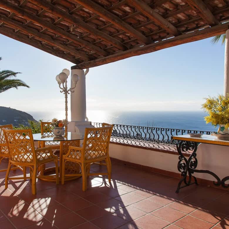 Godimento di una terrazza con vista mare, arredamento elegante e piante tropicali, ideale per relax e cene all'aperto in un ambiente esclusivo e panoramico. Perfetta per case di lusso e proprietà con.