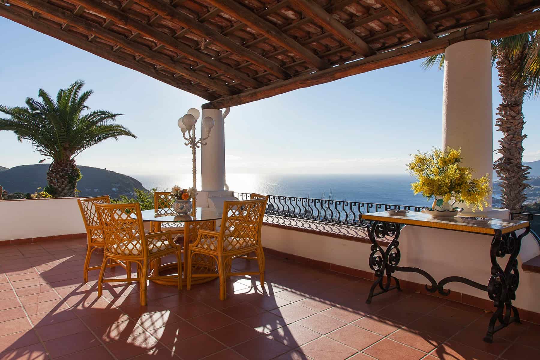 Godimento di una terrazza con vista mare, arredamento elegante e piante tropicali, ideale per relax e cene all'aperto in un ambiente esclusivo e panoramico. Perfetta per case di lusso e proprietà con.