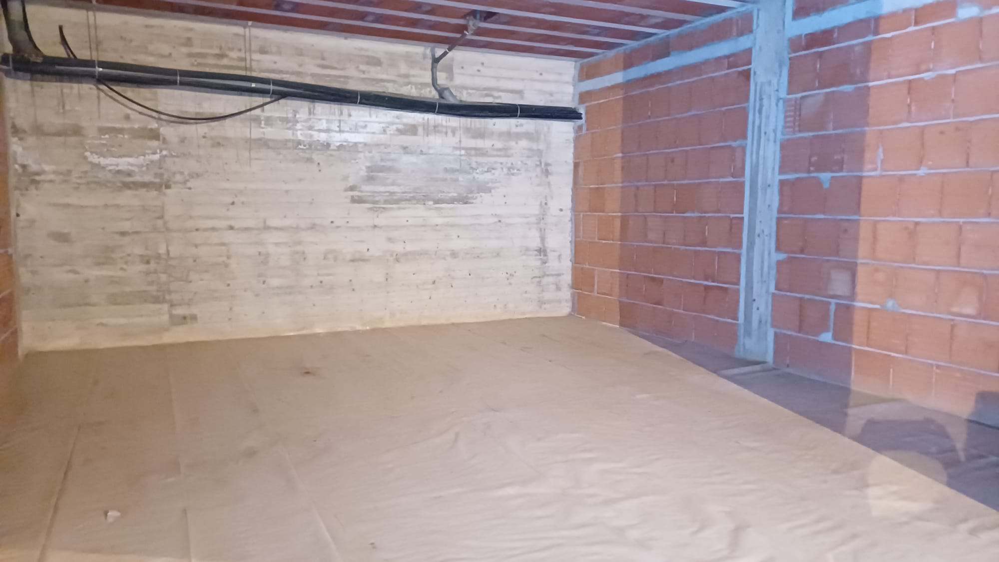 Scaffale vuoto in un ambiente di costruzione o ristrutturazione con pareti in mattoni e cemento, pronto per l'installazione di mobili o sistemi di stoccaggio.