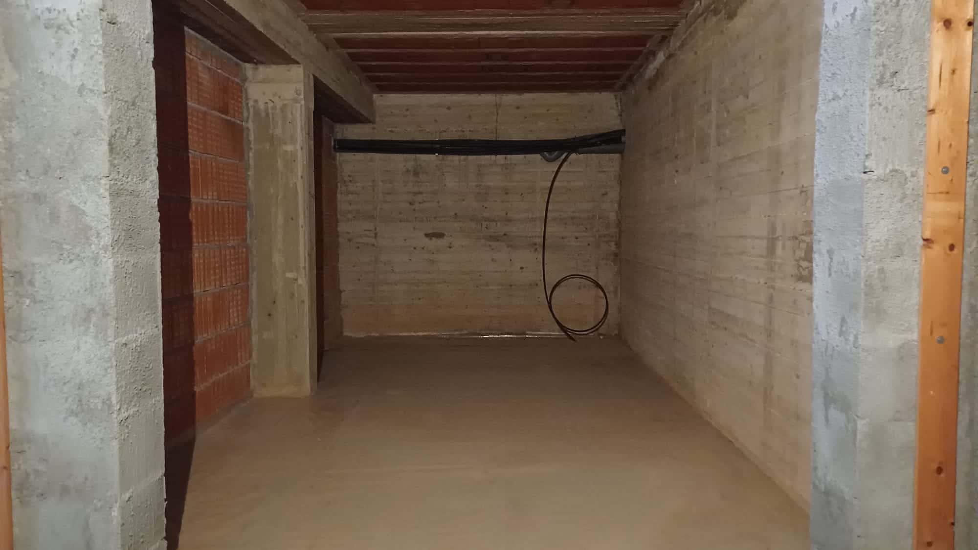 Ampia stanza in costruzione con pareti in cemento e struttura in legno, pronta per essere rifinita come spazio abitativo o ufficio. Ideale per progetti di ristrutturazione e personalizzazione immobili.