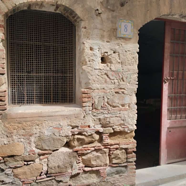 Antico muro in pietra con finestra e porta in legno, stile rustico, in un edificio storico.