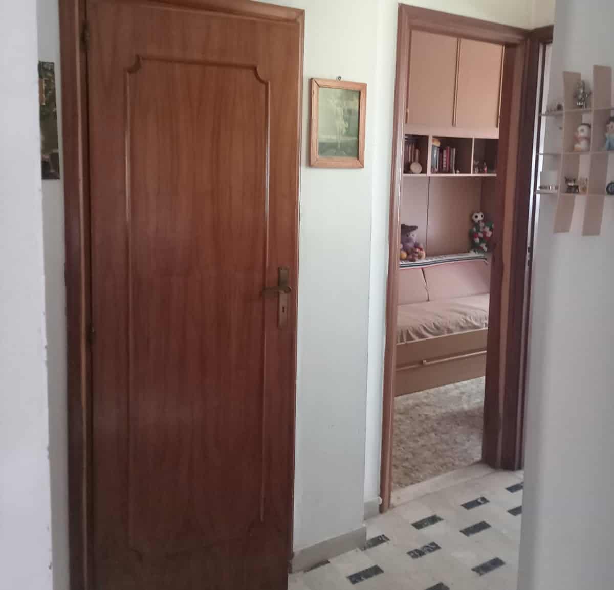 Riproduzione di una porta in legno in un ambiente domestico con vista su una stanza arredata, ideale per immagini di interni di case e appartamenti in vendita o affitto.