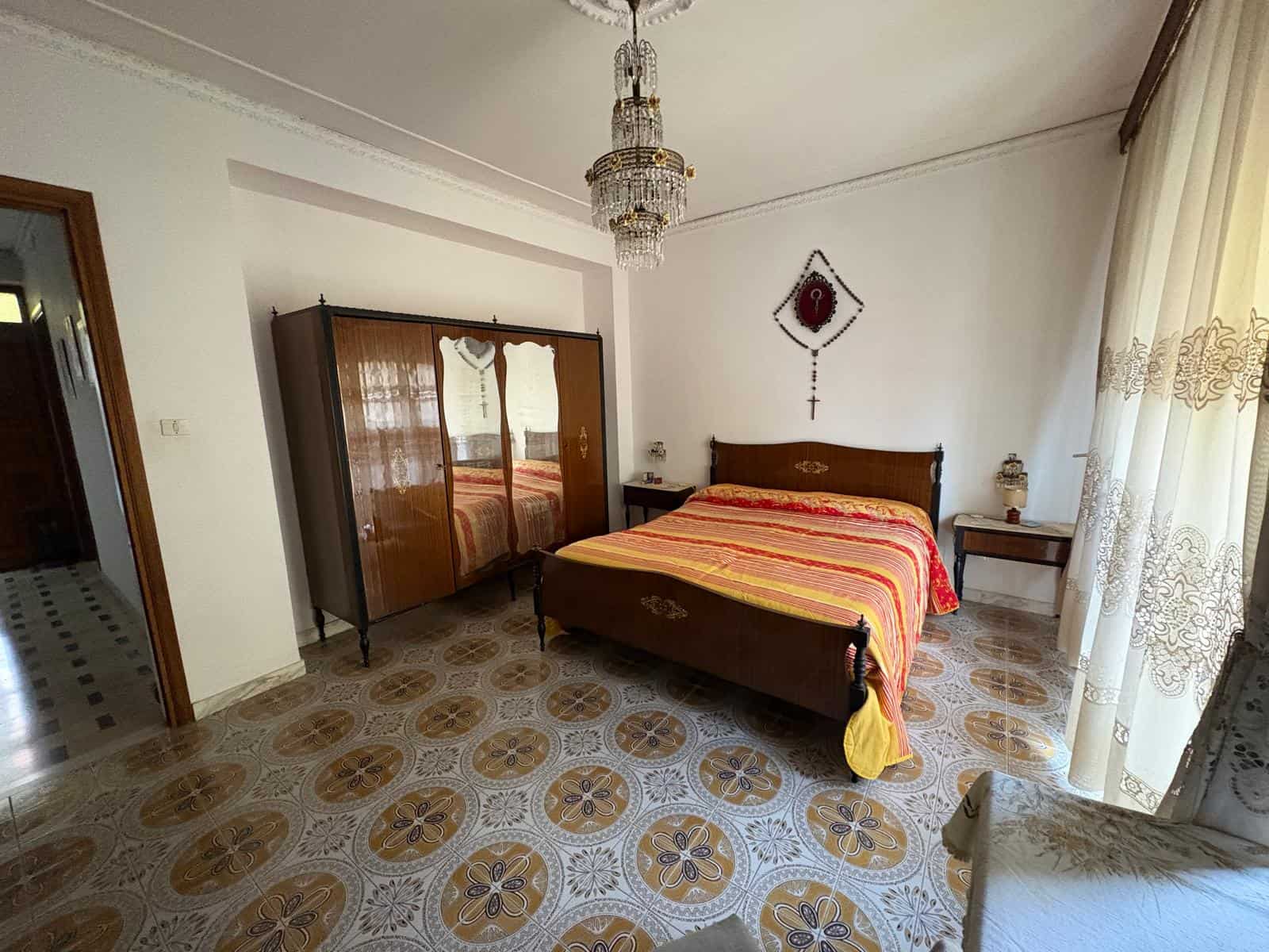 Una stanza da letto spaziosa e luminosa con un letto in legno, armadio antico e decorazioni tradizionali, ideale per un soggiorno confortevole e autentico in stile italiano.