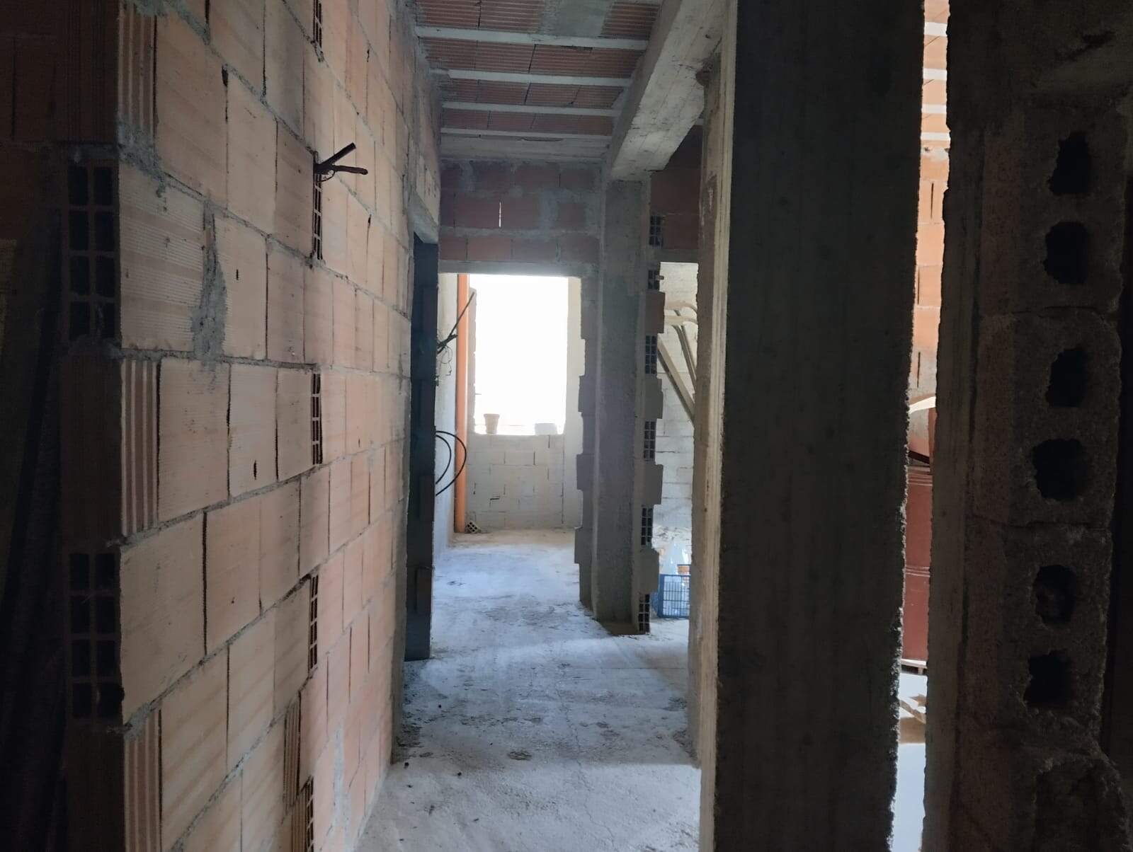 Pareti e strutture in costruzione di un edificio residenziale in fase di sviluppo, con pareti in mattoni e cemento, ambiente interno in costruzione, luce naturale che entra dall'apertura sullo sfondo.