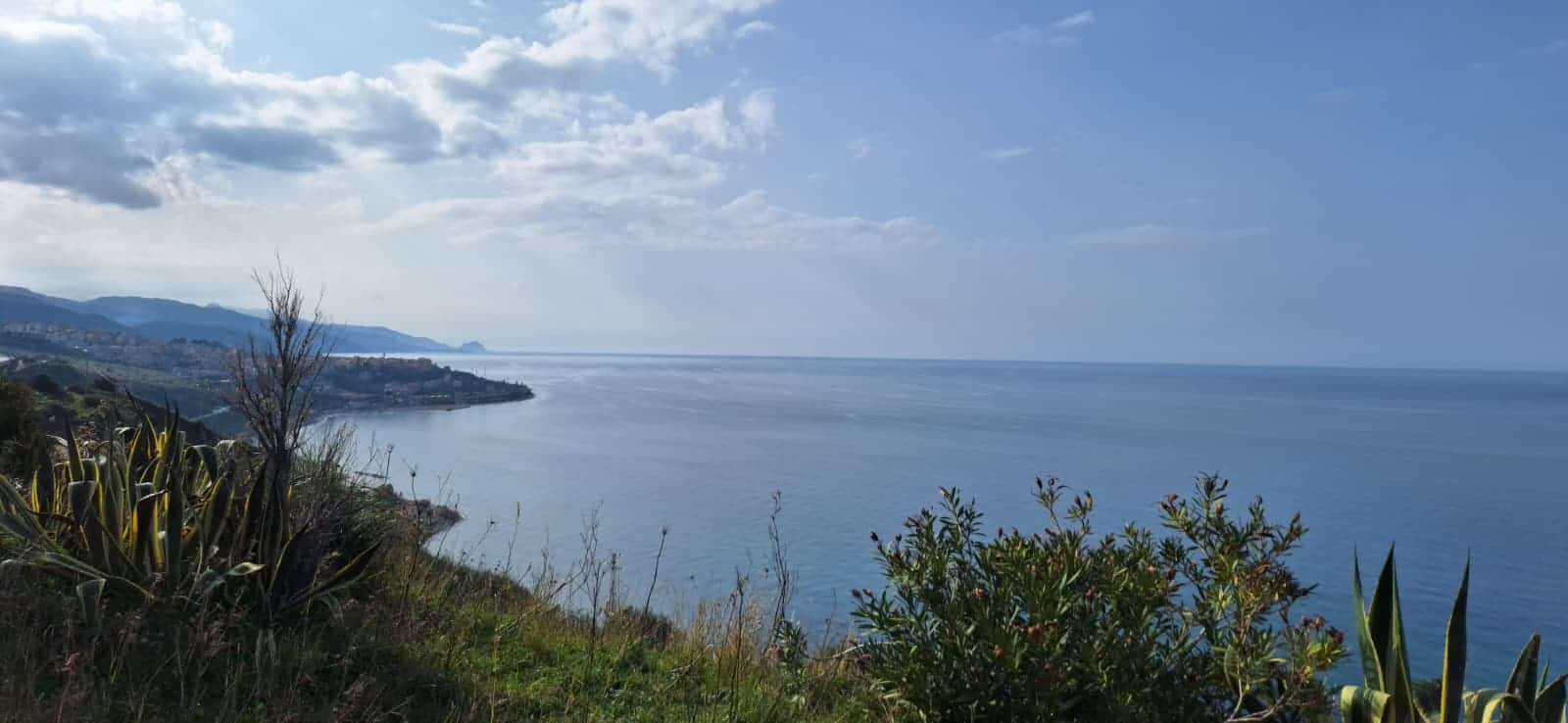 Spiaggia panoramica con vista sul mare e sulla costa, circondata da vegetazione mediterranea, ideale per case vacanze e investimenti immobiliari in località costiere italiane.