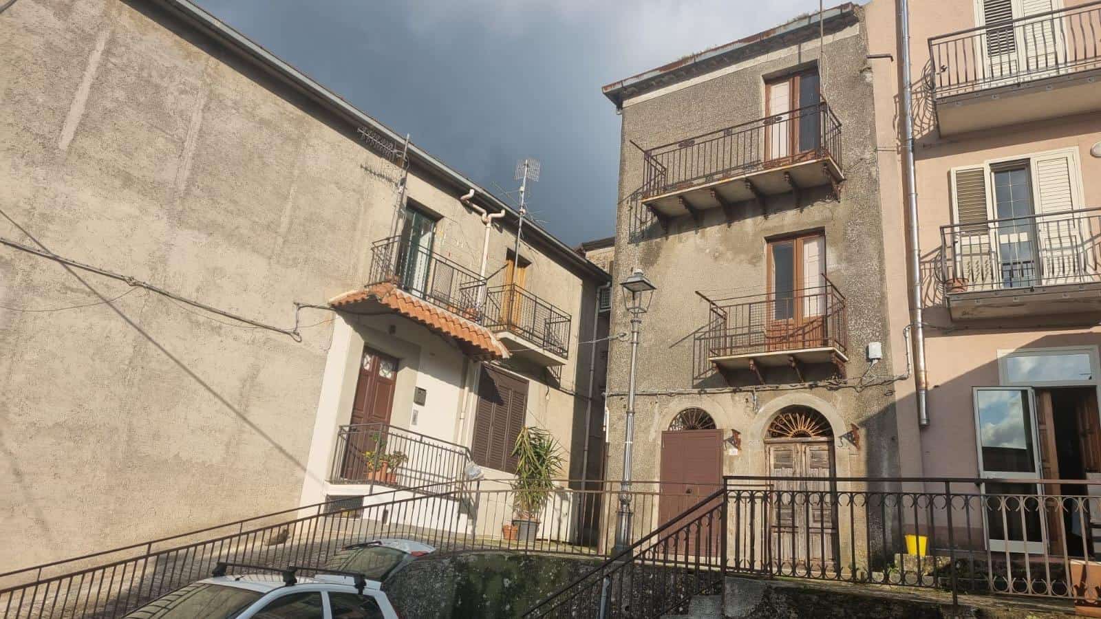 Esterno di un edificio storico con balconi in ferro battuto e pareti in pietra, in un quartiere residenziale di città, con cielo nuvoloso sullo sfondo.