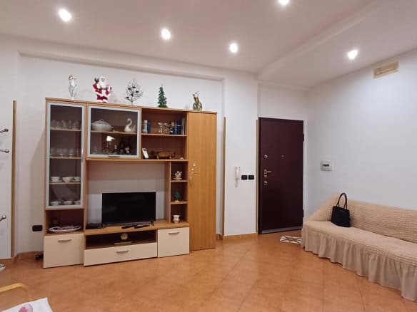 Elegante soggiorno con mobile porta TV, divano beige e decorazioni natalizie, ideale per vivere momenti di relax e convivialità in un ambiente accogliente e ben illuminato.