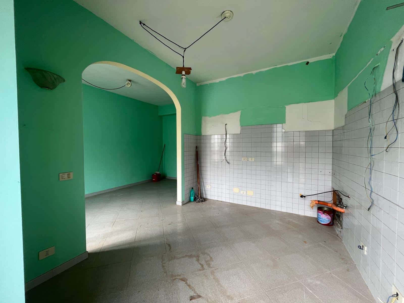Aggiunta di un'immagine di un interno di casa in fase di ristrutturazione, con pareti verdi e cavi elettrici scoperti.