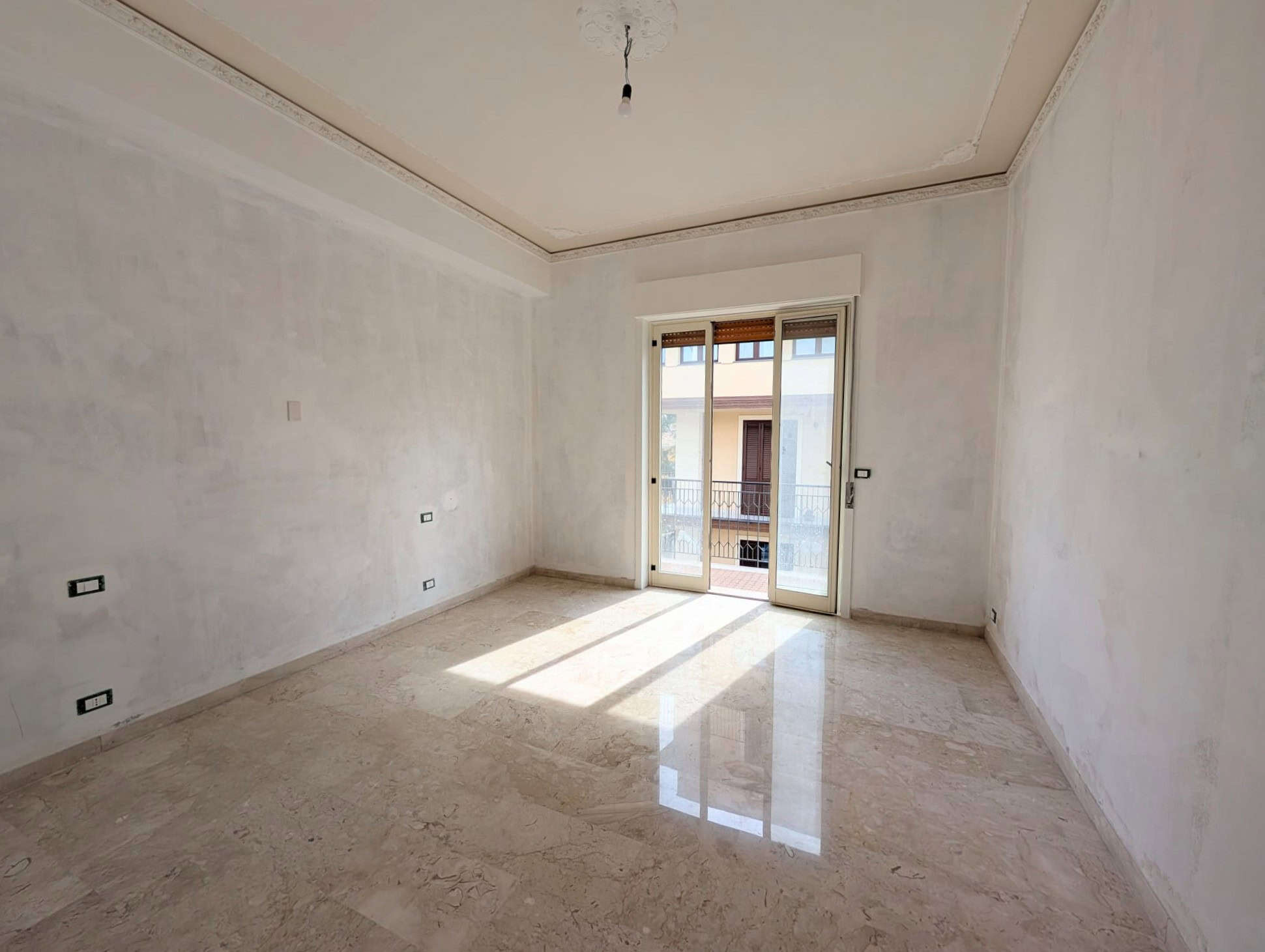 Ampio soggiorno luminoso con pareti bianche e grande finestra che permette l'ingresso di luce naturale, ideale per ambienti moderni e accoglienti.