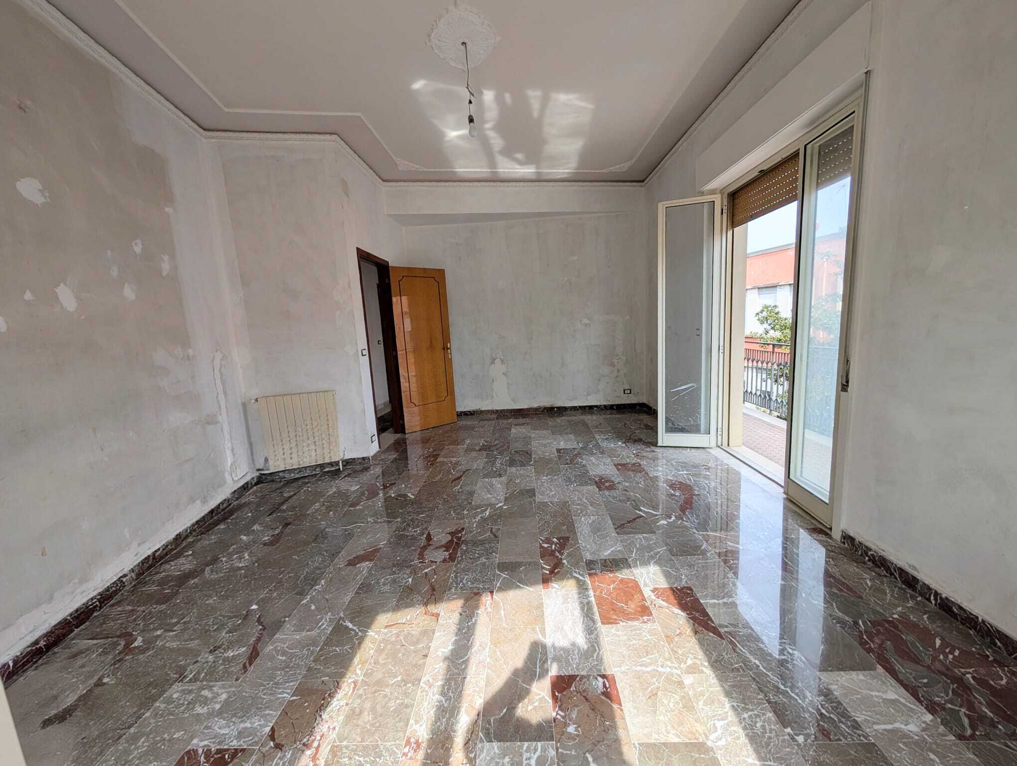Appartamento vuoto con pareti da ristrutturare e grande balcone con vista sulla città, ideale per personalizzare gli spazi e creare un ambiente accogliente.