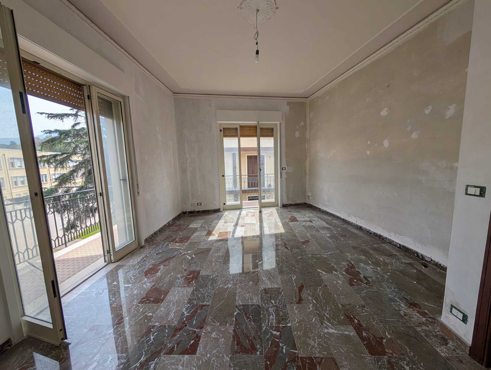 Appartamento in fase di ristrutturazione con grandi finestre e balcone, luminoso e spazioso, pronto per essere personalizzato. Ideale per chi cerca una casa moderna e funzionale.