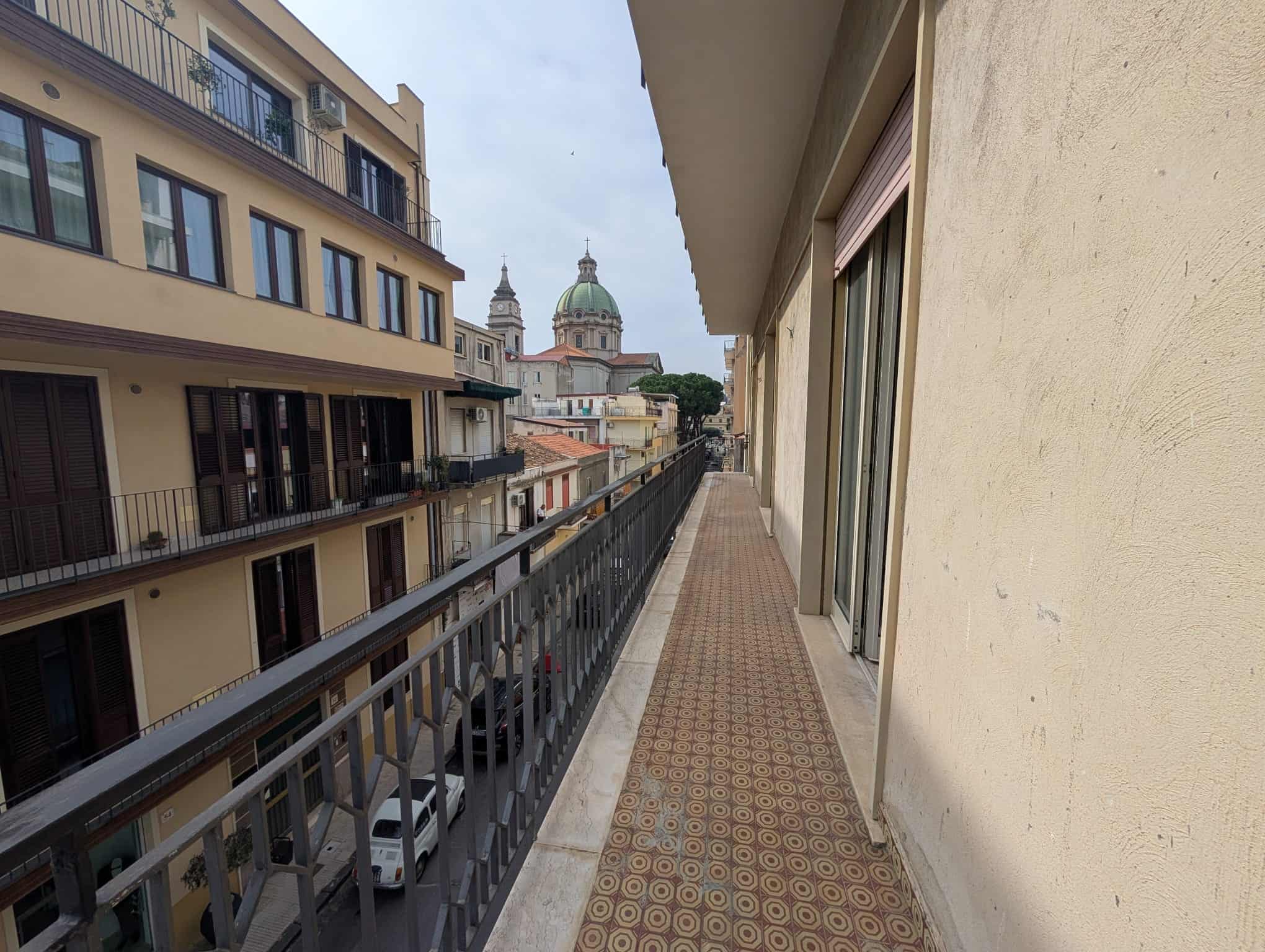 Balcone di un appartamento con vista sulla città e chiese storiche, in un contesto urbano con edifici moderni e antichi, ideale per vivere o affittare in zona centrale e ben collegata.