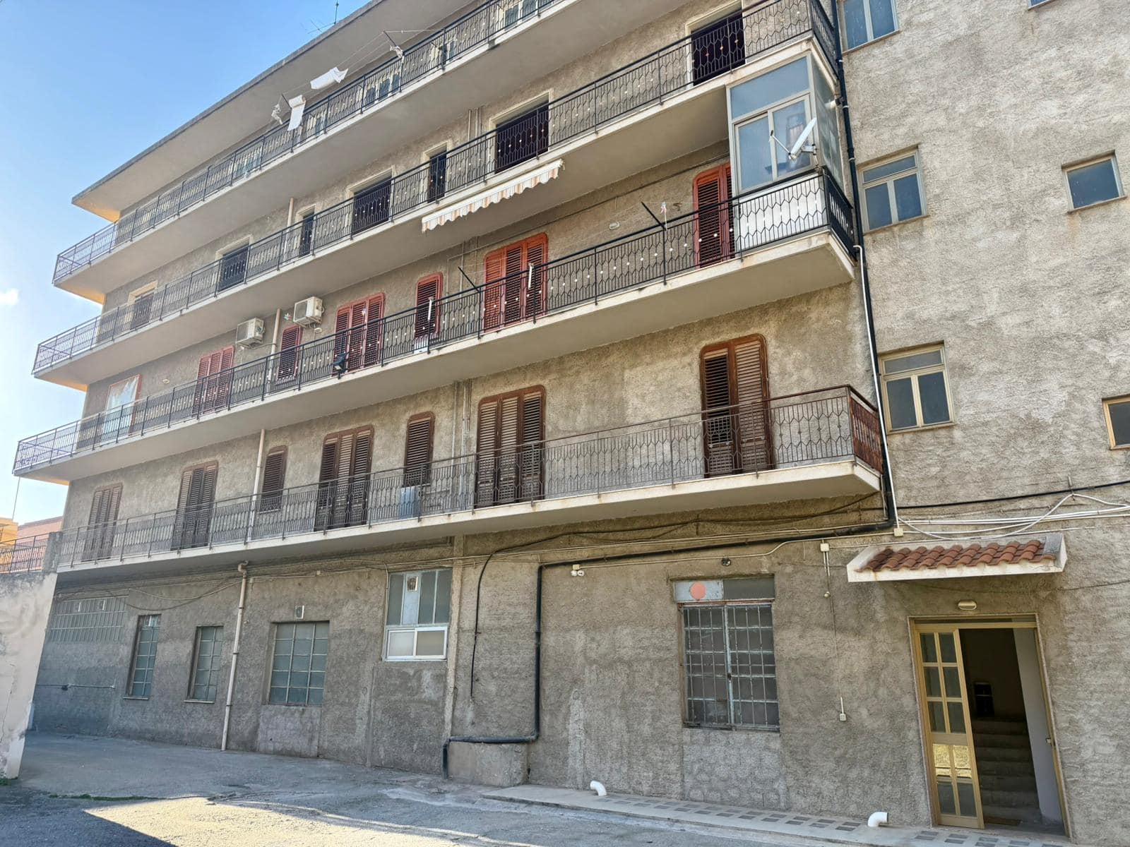 Pannelli di balcone in ferro battuto e facciata esterna di un edificio residenziale in stile urbano, con dettagli di finestre e porta d'ingresso.