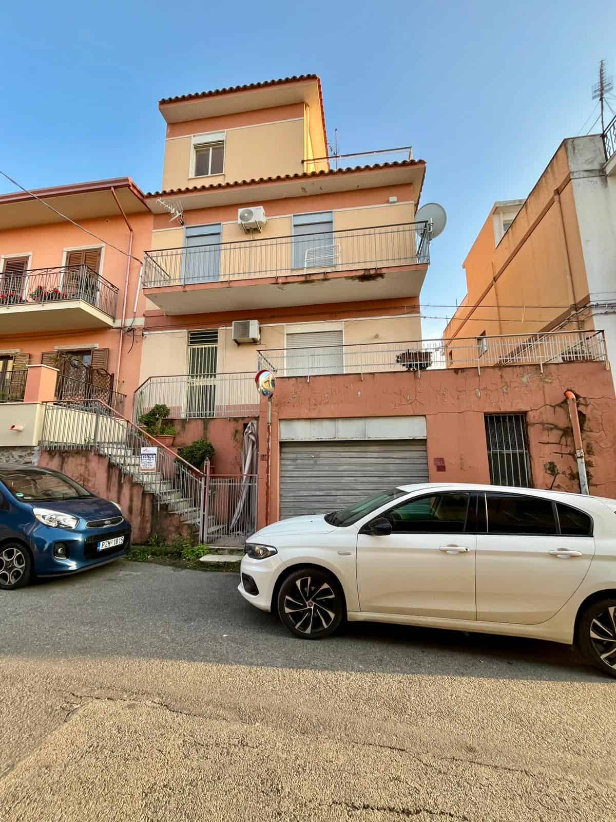 Edificio residenziale a tre piani con balconi, aria condizionata e parcheggio in strada, in zona urbana di NextCasa, Italia.