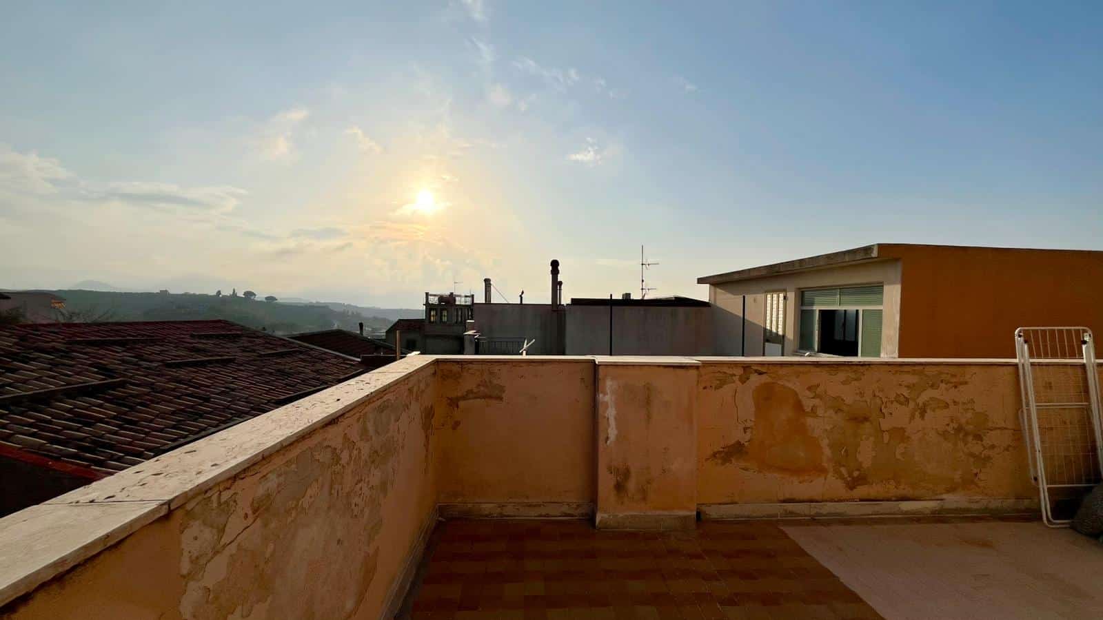 Vista panoramica di un terrazzo con cielo sereno e sole al tramonto, in un contesto urbano, ideale per immobili residenziali e investimenti immobiliari a NextCasa.