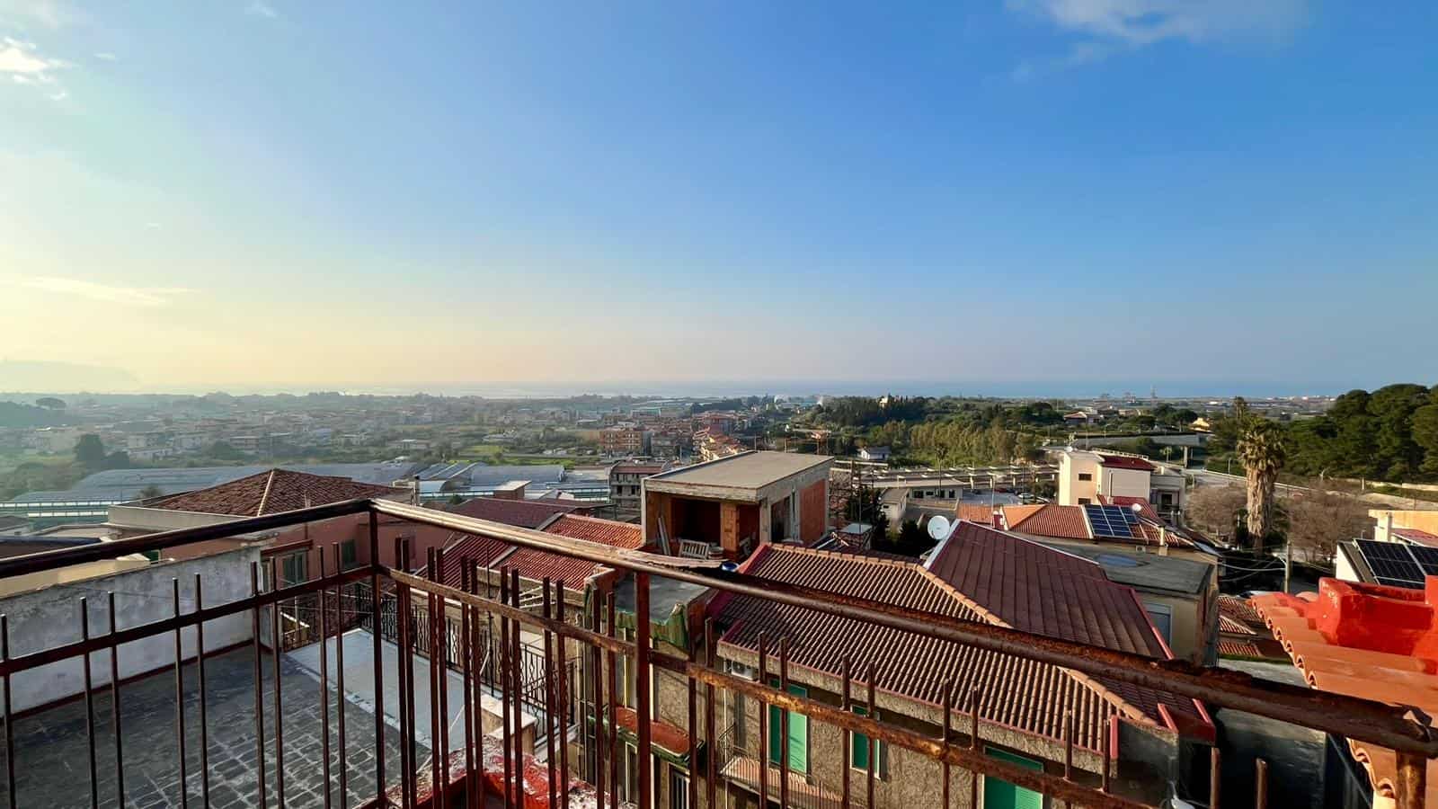 Vista panoramica di case residenziali con tetti in tegole e pannelli solari, sotto un cielo sereno, rappresentando soluzioni di abitazioni sostenibili e innovative a NextCasa.