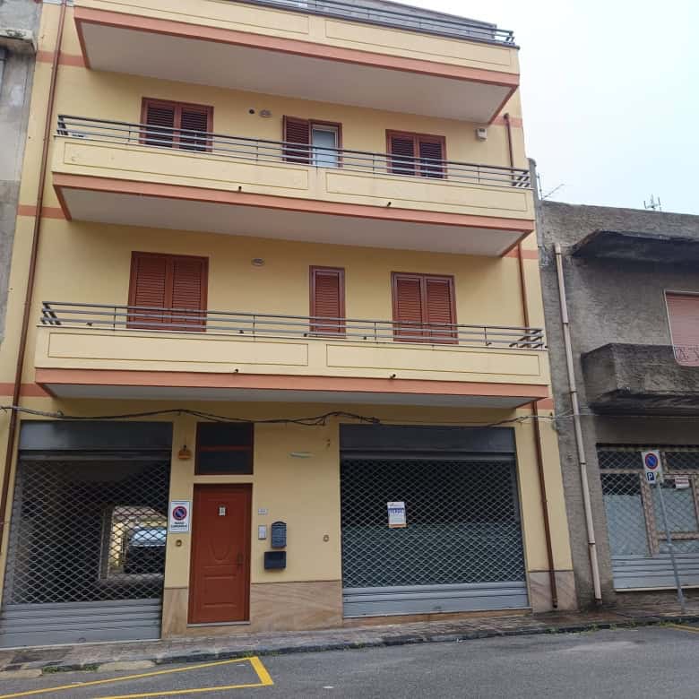 Porte blindate e balconi in ferro su edificio residenziale a Napoli, Italia, con facciata gialla e dettagli in legno, in zona urbana con negozi e servizi nelle vicinanze.