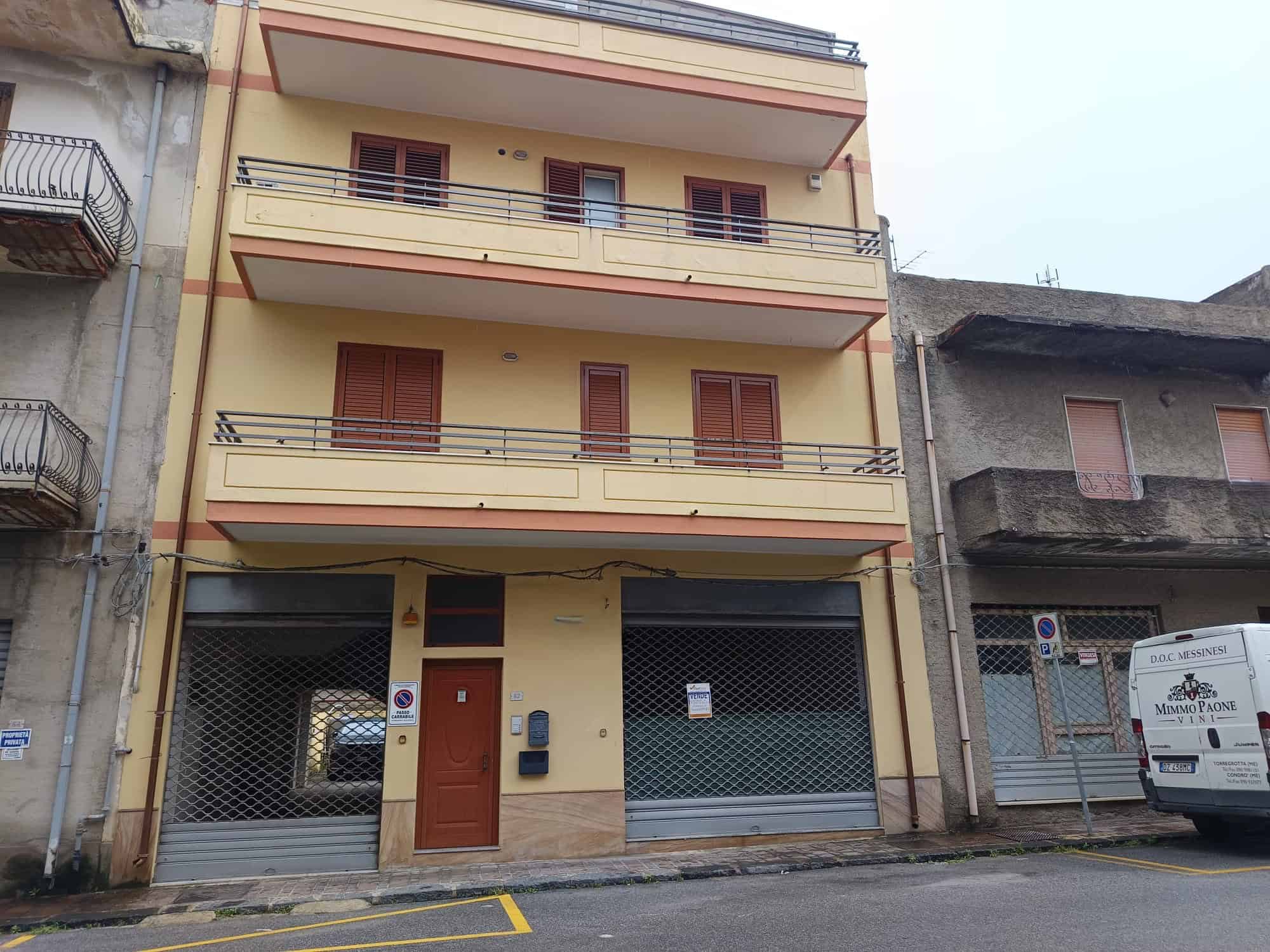 Porte blindate e balconi in ferro su edificio residenziale a Napoli, Italia, con facciata gialla e dettagli in legno, in zona urbana con negozi e servizi nelle vicinanze.
