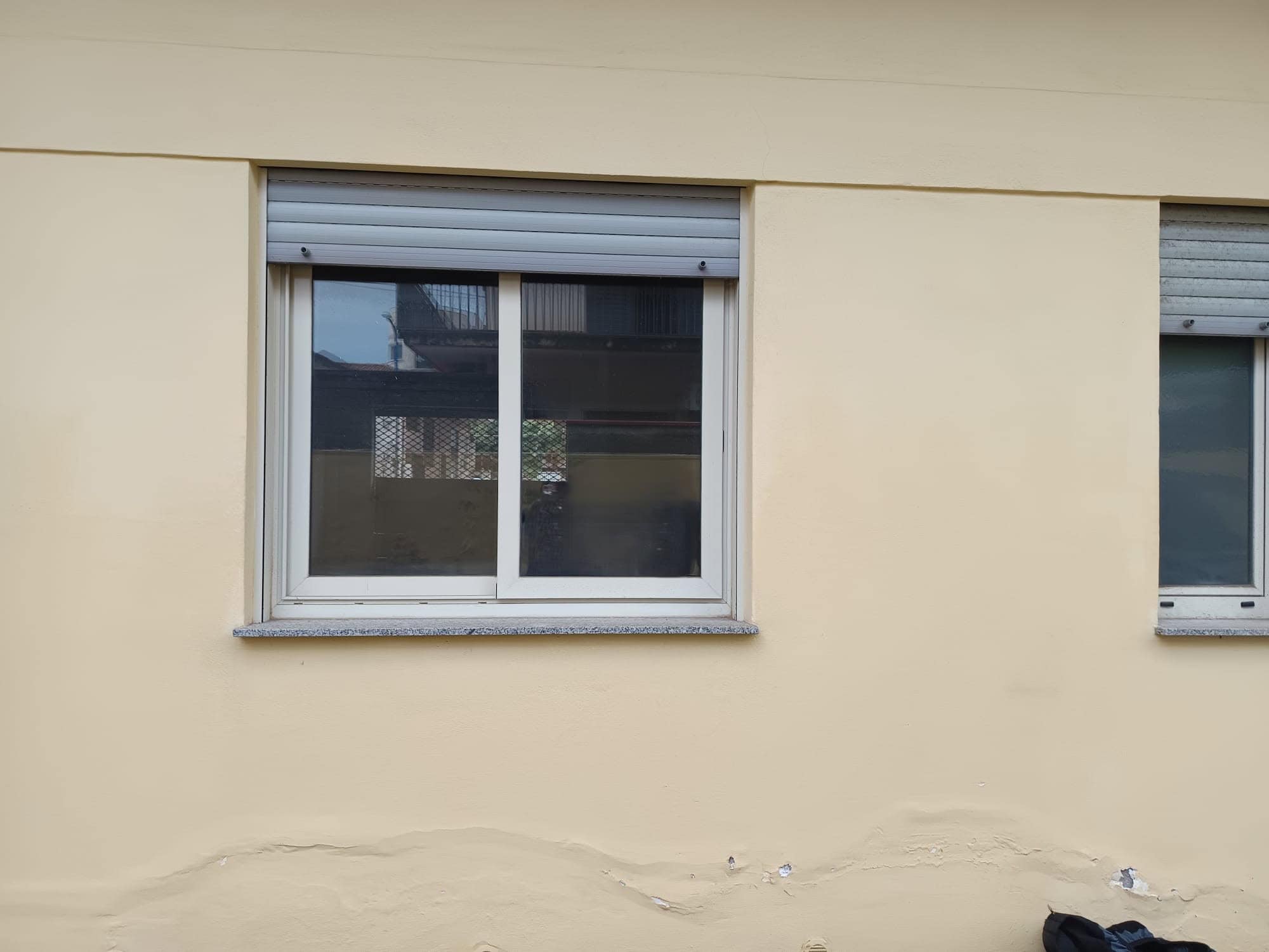 Persiana avvolgibile esterna su finestra in parete beige, edificio residenziale moderna.