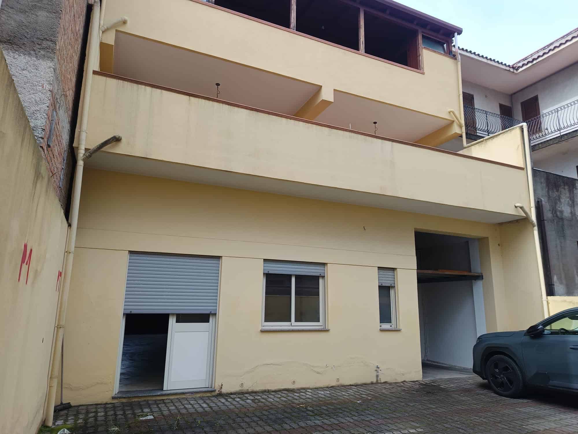 Ampio edificio residenziale con facciata gialla, balconi e finestre moderne, situato in zona urbana con parcheggio privato e accesso carraio.