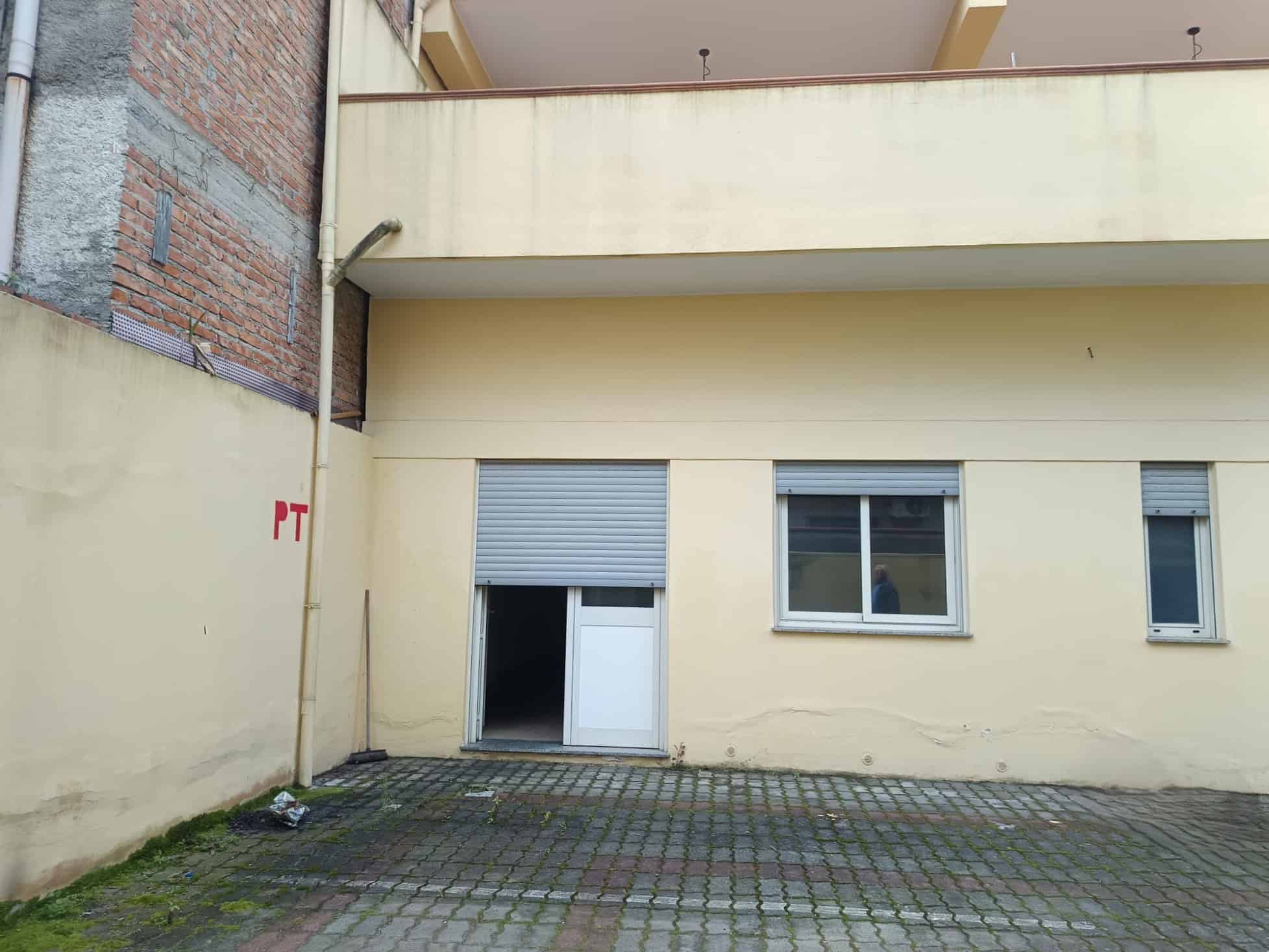 Ampio cortile esterno con pareti beige e pavimentazione in pietra, ideale per attività all'aperto e parcheggio. Spazio versatile vicino a edifici residenziali, perfetto per ristrutturazioni o investim.