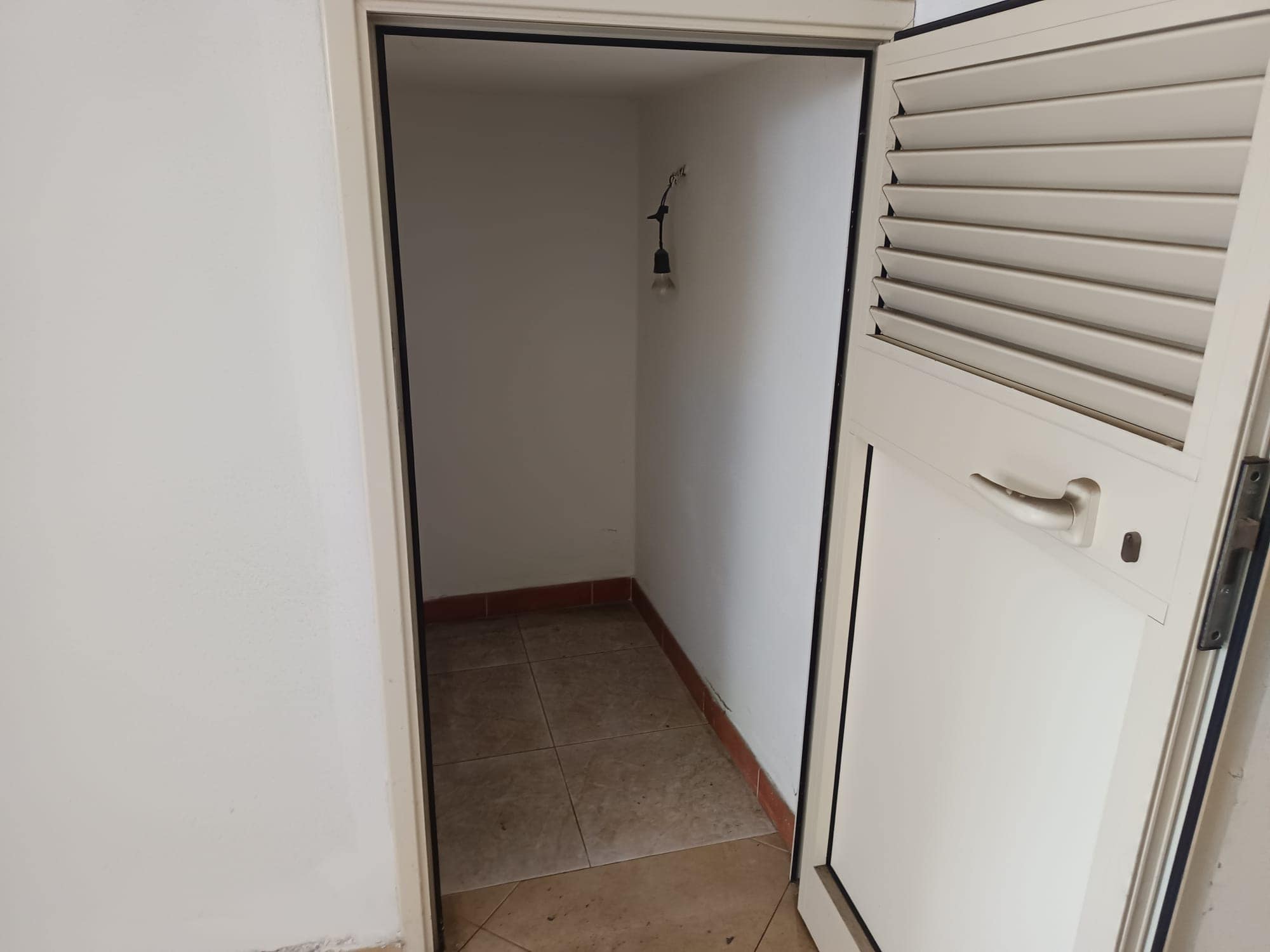 Una nicchia o ripostiglio vuoto con pareti bianche e pavimento in piastrelle, ideale per spazio di stoccaggio o armadio in un ambiente domestico.
