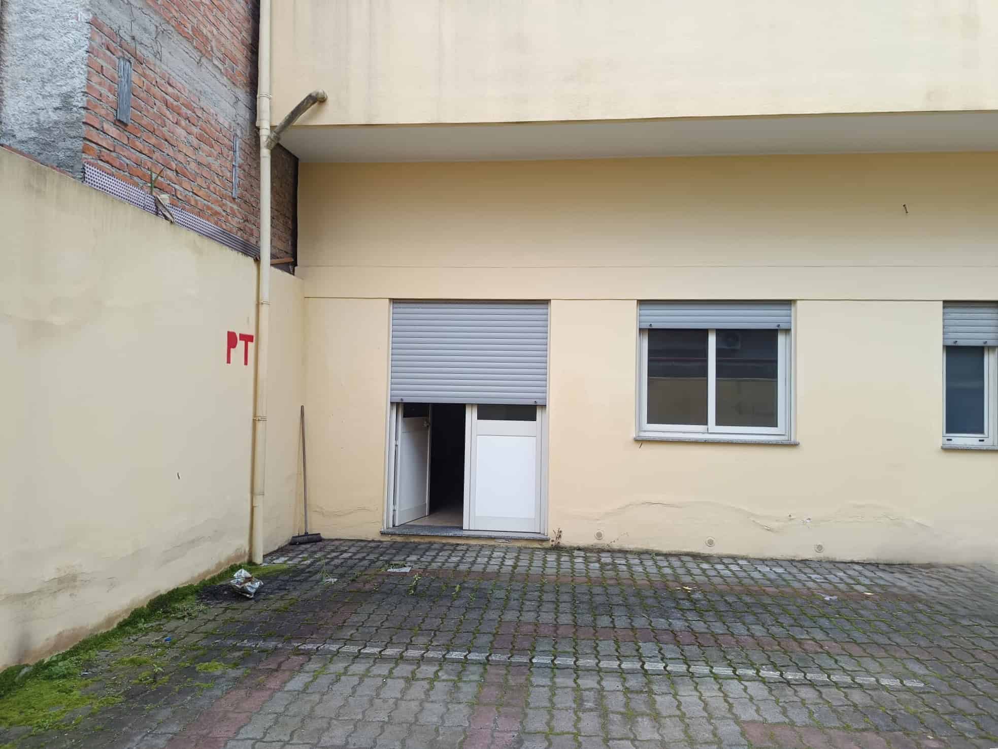 Porta finestra con tapparella e finestra in un cortile esterno di un edificio residenziale, con pavimentazione in pietra e pareti beige.