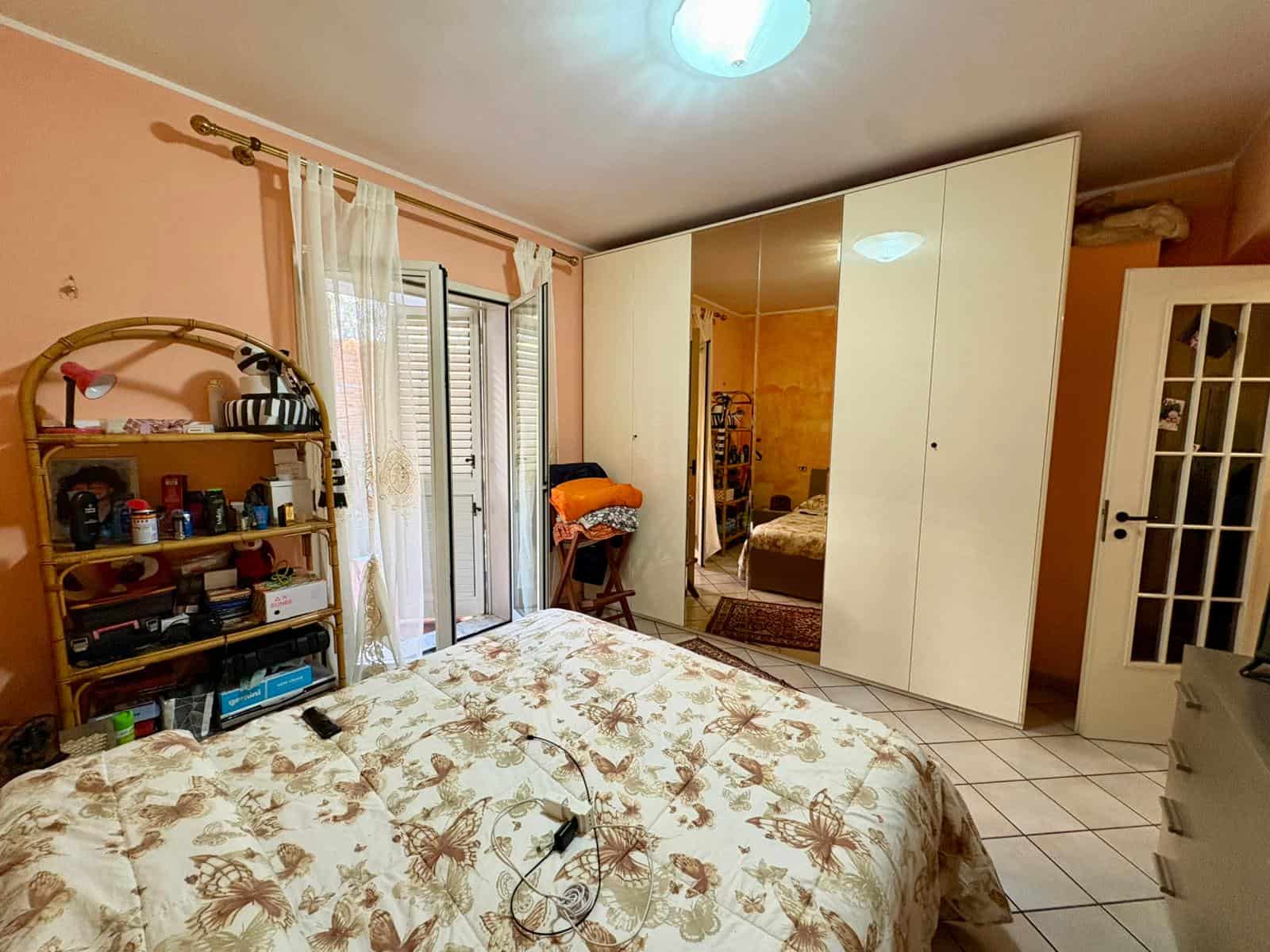 Coppia di immagini di una camera da letto con armadio a specchio, letto matrimoniale e accessori vari, ambiente luminoso e accogliente, ideale per la vendita o l'affitto di immobili residenziali.