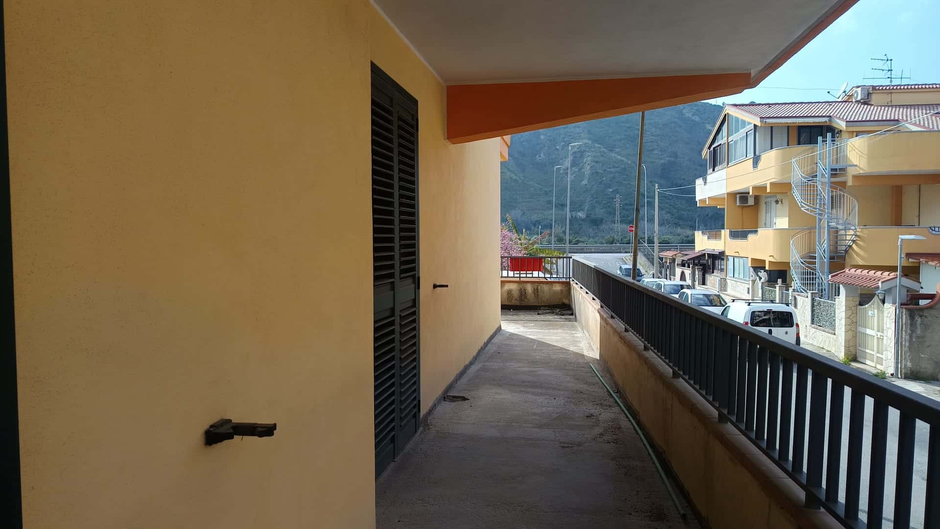 Ampio balcone con vista sulle montagne e sulle case circostanti, ideale per relax e momenti all'aperto in un contesto residenziale tranquillo.