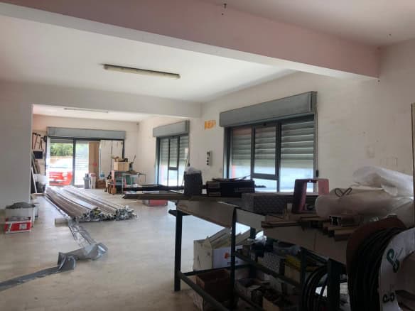 Interno di un appartamento in fase di ristrutturazione con materiali e attrezzi da lavoro, luce naturale e finestre con tapparelle.
