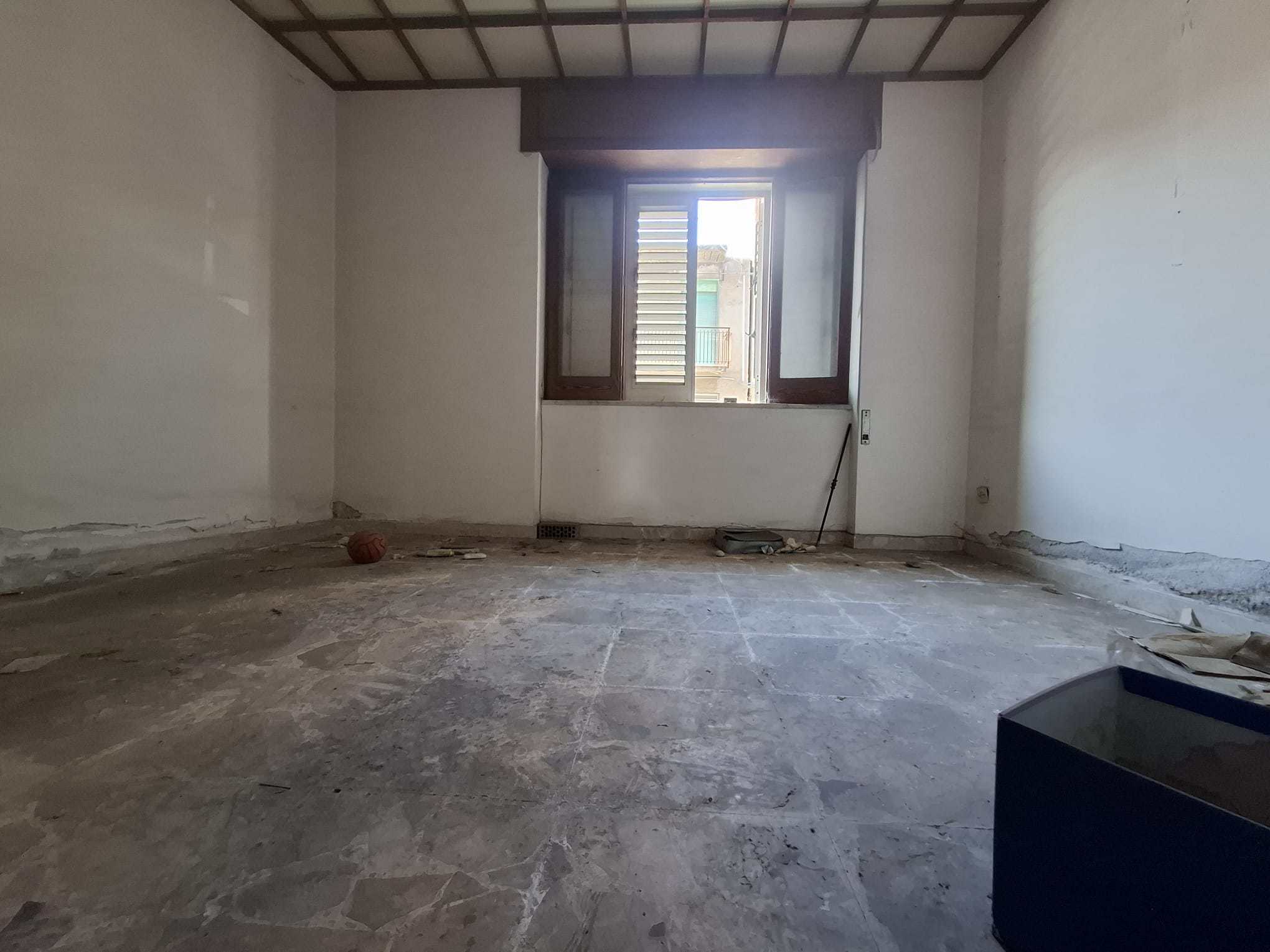 Ampio ambiente vuoto in fase di ristrutturazione con pareti bianche e finestra grande, pronto per essere arredato e personalizzato.