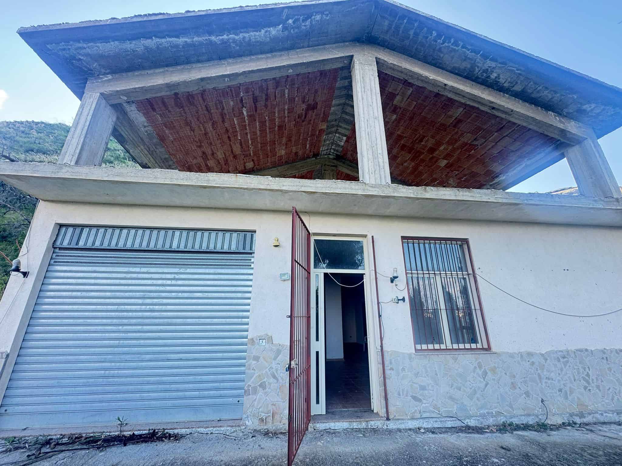 Pannello solare sul tetto di una casa moderna con garage e finestra, in un'area rurale con paesaggi montani sullo sfondo, ideale per investimenti immobiliari sostenibili.