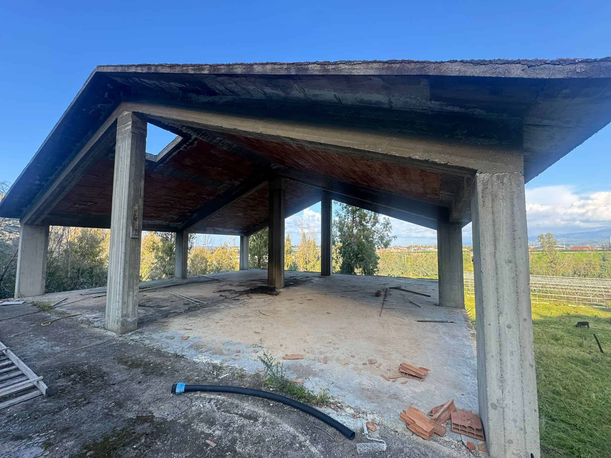 Pannello di copertura in cemento con struttura in cemento armato, situato in un'area aperta con vista su campi e cielo sereno, ideale per progetti di costruzione o ristrutturazione.
