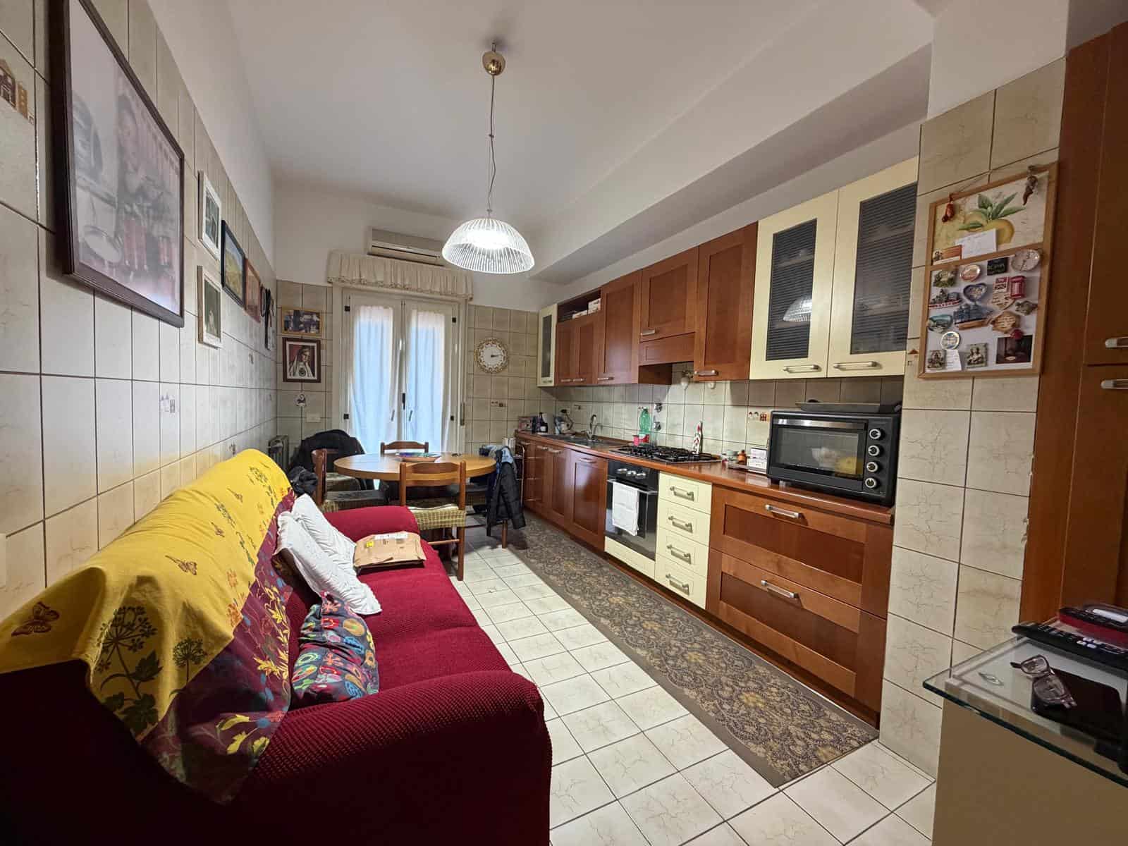 Appartamento con cucina abitabile e zona soggiorno, arredi funzionali e decorazioni accoglienti, ideale per vivere in comfort e stile. Spazio luminoso con accesso a balcone e dettagli pratici.