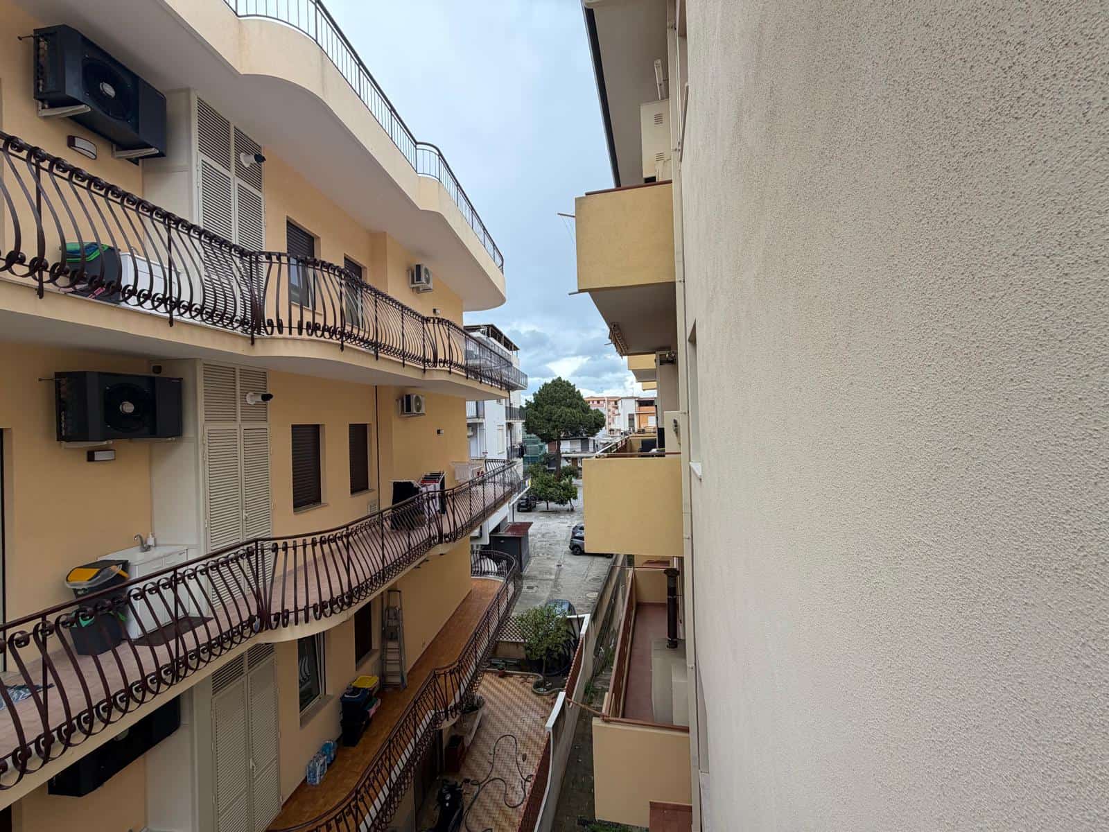 Lavatrice e aria condizionata sui balconi di un edificio residenziale a più piani, vista da un balcone.