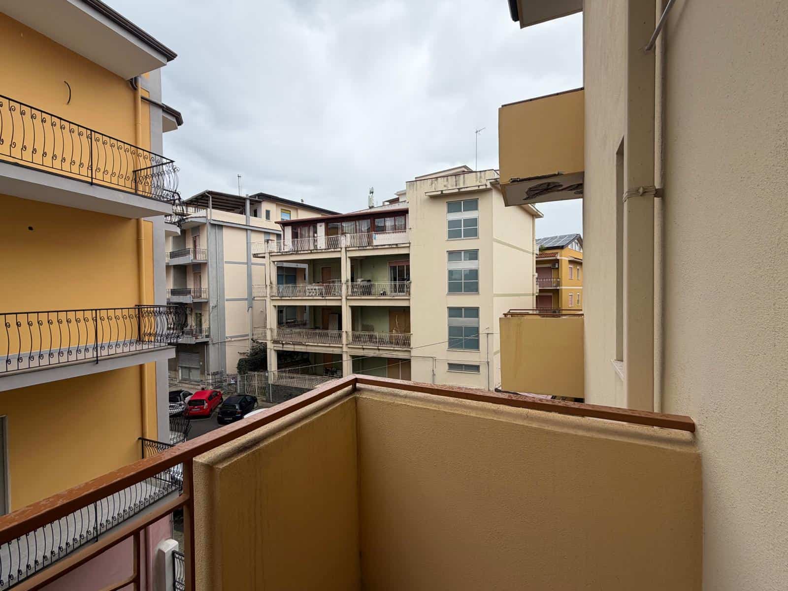 Balcone di un appartamento in un complesso residenziale urbano con edifici moderni e balconi, vista su altre strutture abitative, cielo nuvoloso, atmosfera tranquilla e urbana.