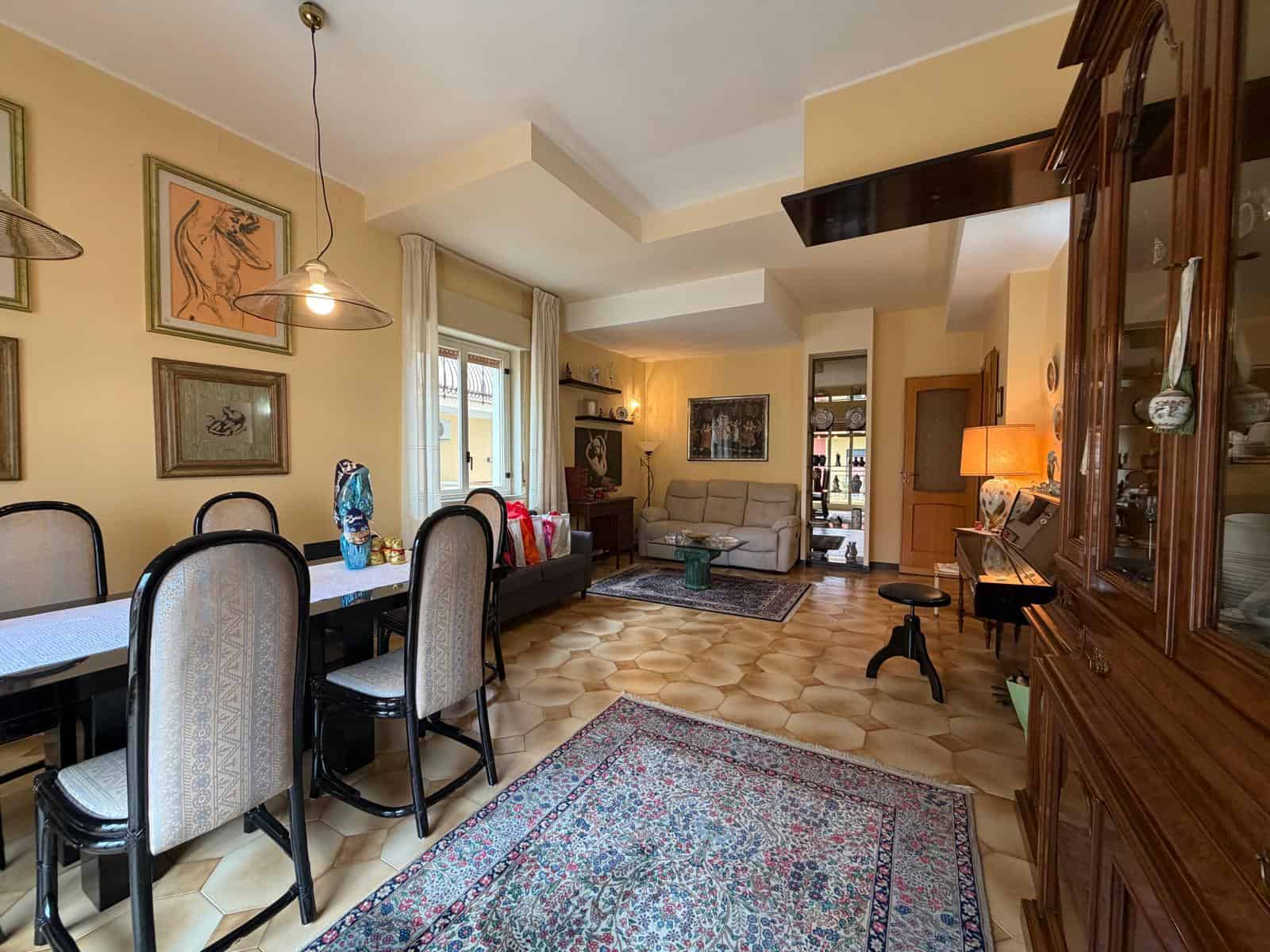 Il soggiorno spazioso e luminoso con mobili eleganti, pareti decorate e un'area pranzo accogliente, ideale per vivere momenti di relax e convivialità in un ambiente raffinato.