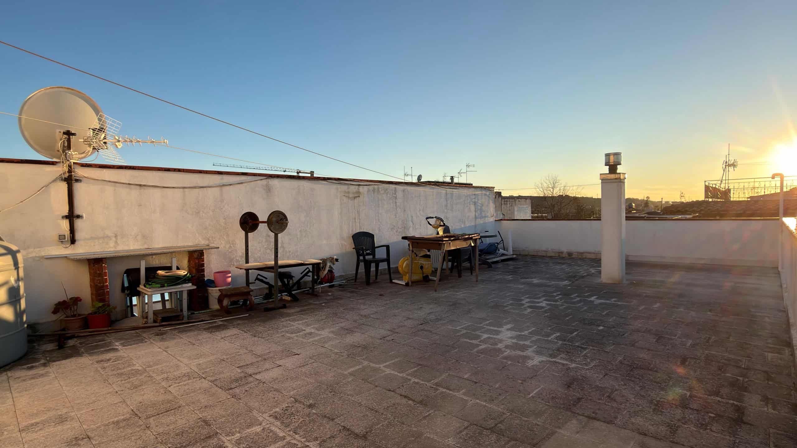 Ampia terrazza sul tetto con vista al tramonto, arredi da esterno e attrezzature per il relax e la convivialità, ideale per vivere momenti all'aperto in un ambiente tranquillo e panoramico.