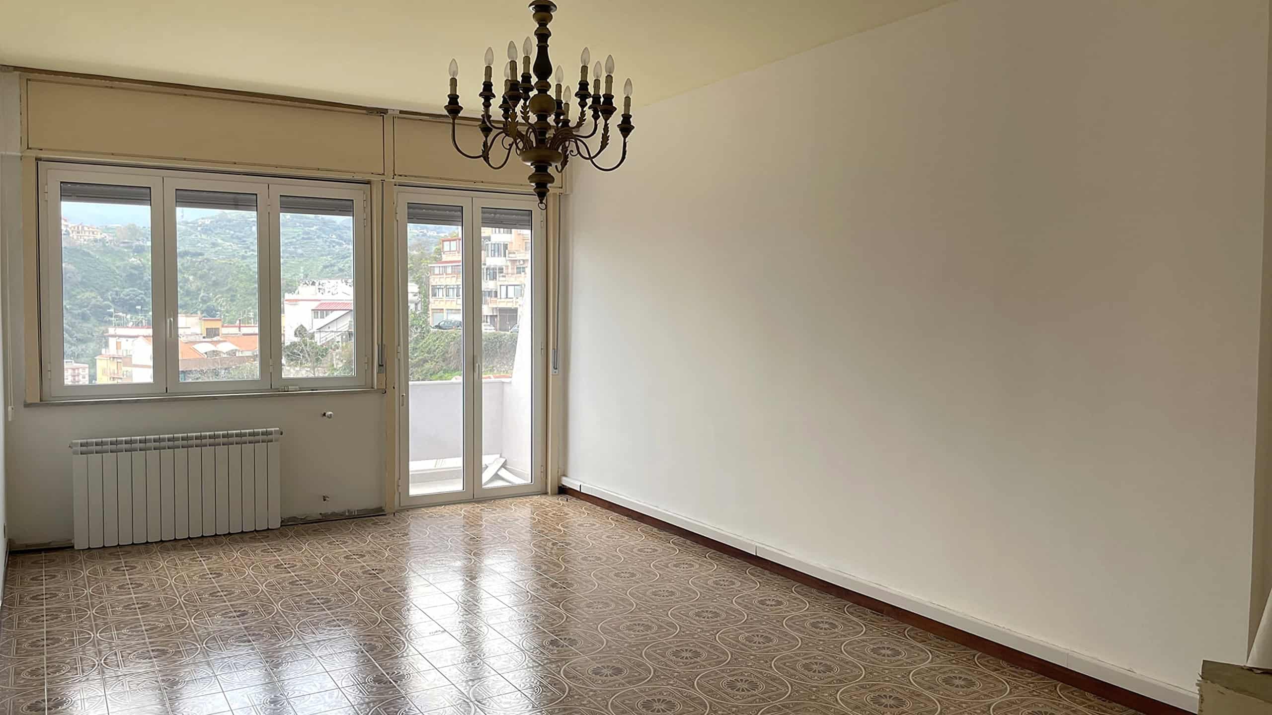 Ampio soggiorno luminoso con grandi finestre e balcone, ideale per vivere e rilassarsi in casa.