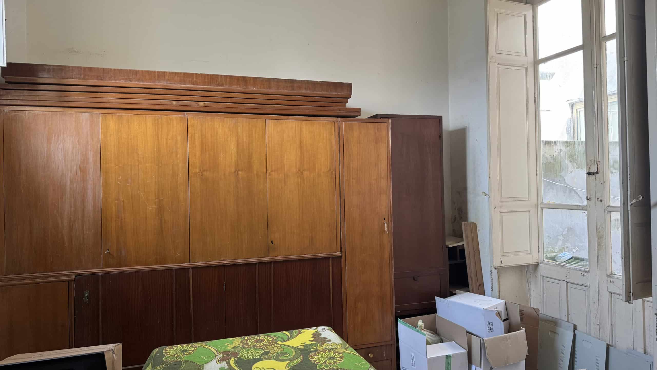 Armadio in legno massiccio in una stanza luminosa con grandi finestre, ideale per arredamento classico e funzionale.