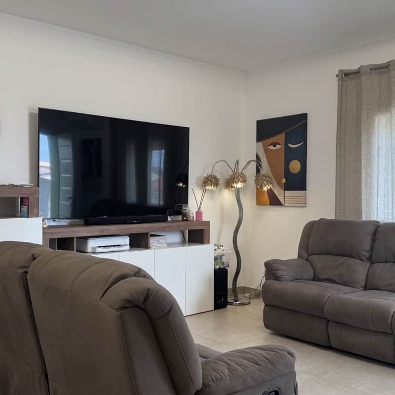 Elegante soggiorno con divani in tessuto grigio, TV a schermo piatto e decorazioni moderne, ideale per vivere momenti di relax e convivialità in un ambiente accogliente e ben arredato.