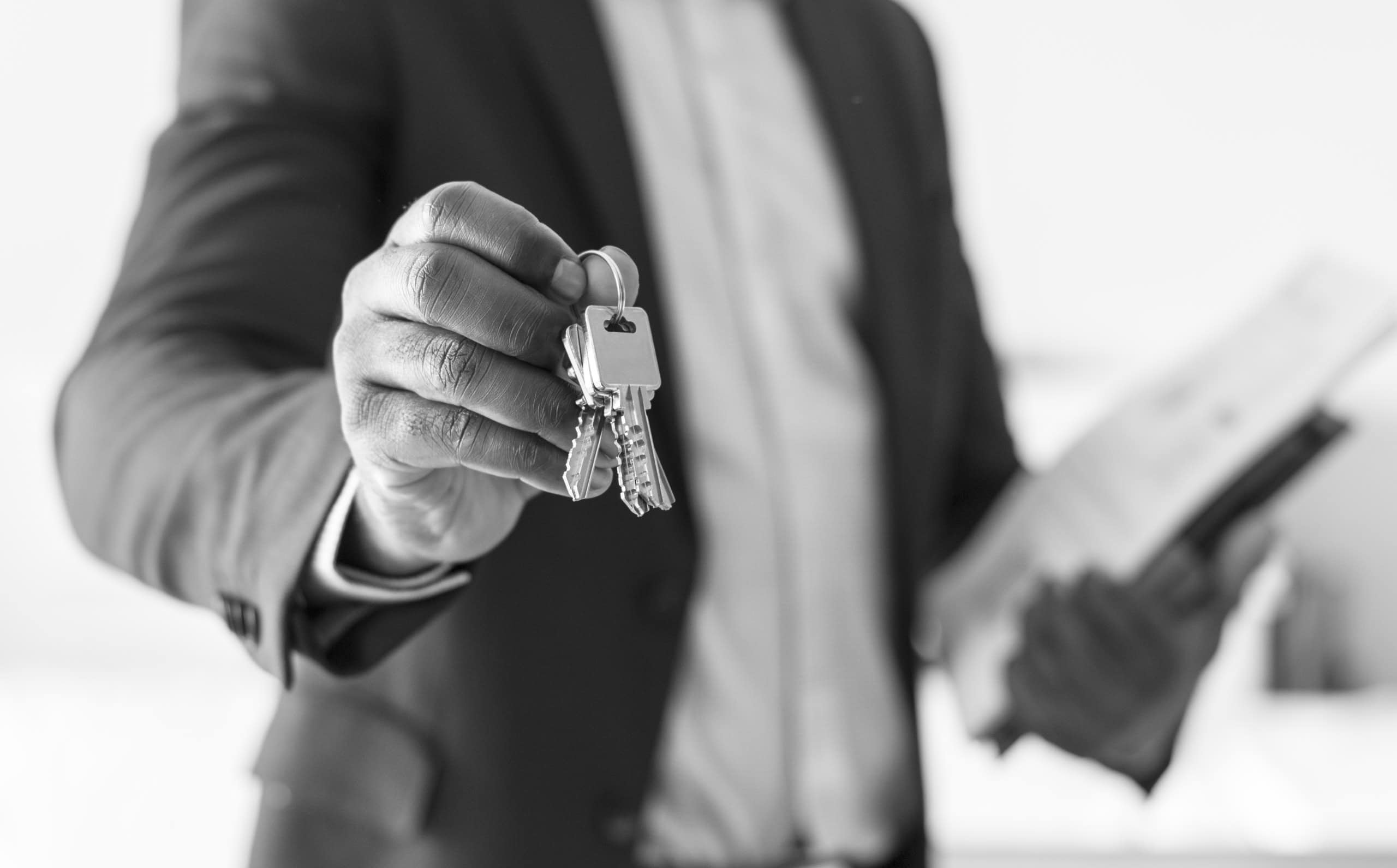 Chiavi in mano di un agente immobiliare che consegna le chiavi di una proprietà, simbolo di vendita o affitto di immobili, rappresentando professionalità e fiducia nel settore immobiliare.