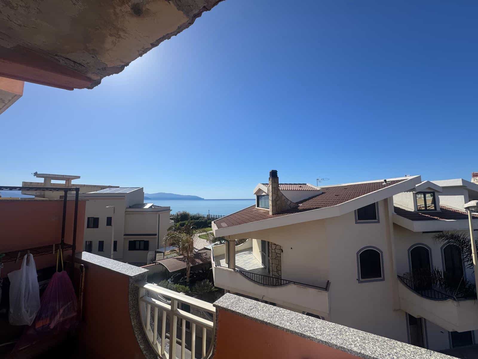 Vista mare da un balcone con case moderne e cielo sereno.
