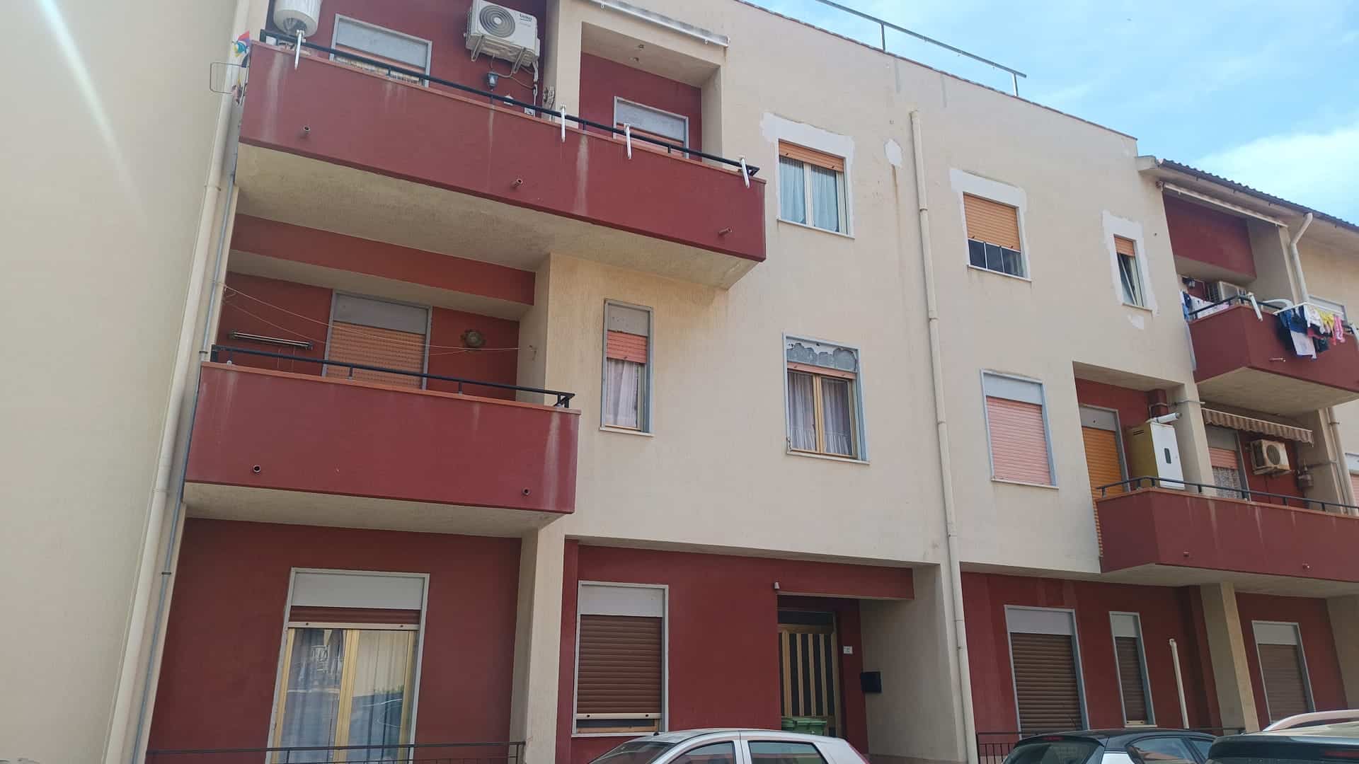 Appartamento residenziale in edificio multifamiliare con balconi e finestre, facciata in tonalità beige e rosso, con aria condizionata installata.