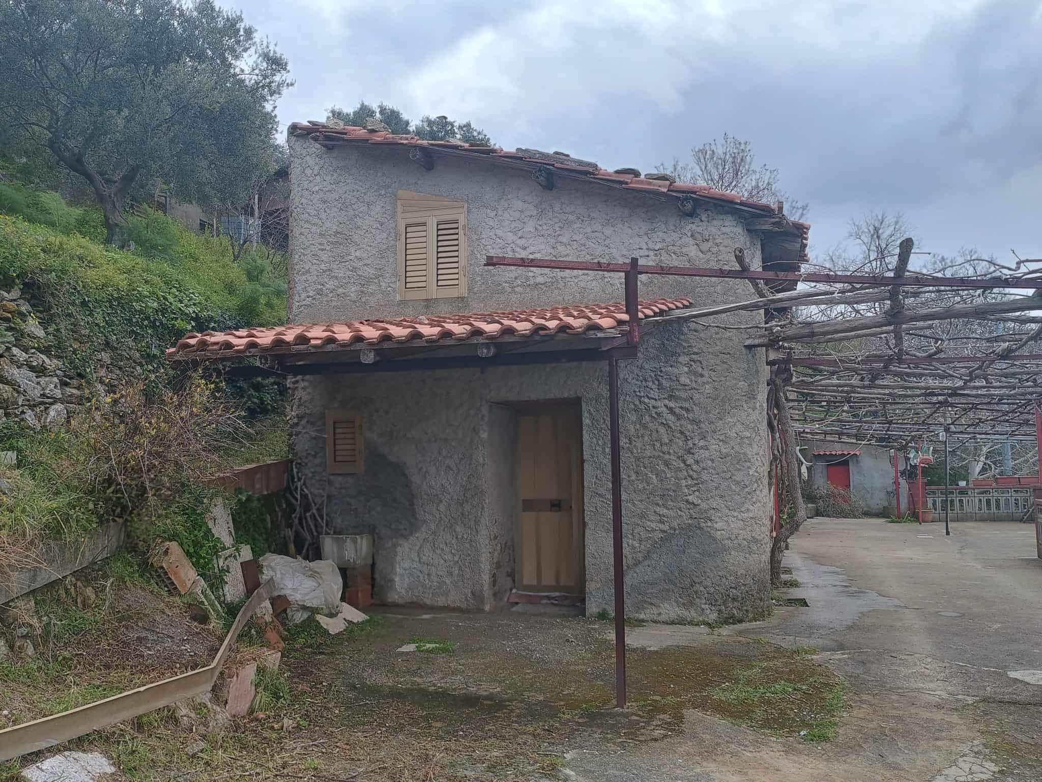 Casa in pietra rustica con tetto in terracotta, immersa nella campagna, ideale per chi cerca tranquillità e charme storico.