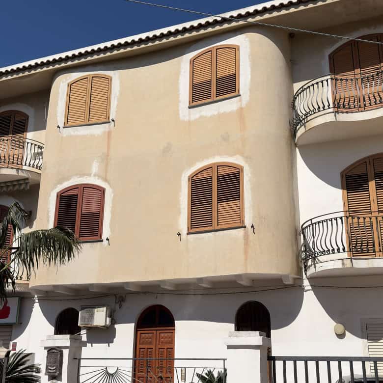 Edificio residenziale con balconi e finestre in stile classico, facciata beige e tetto in tegole, situato in zona urbana soleggiata.