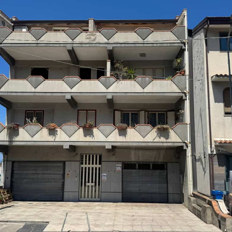 Balcone e facciata di un edificio residenziale con tre piani, balconi con ringhiere geometriche e piante ornamentali, in un contesto urbano soleggiato e moderno.