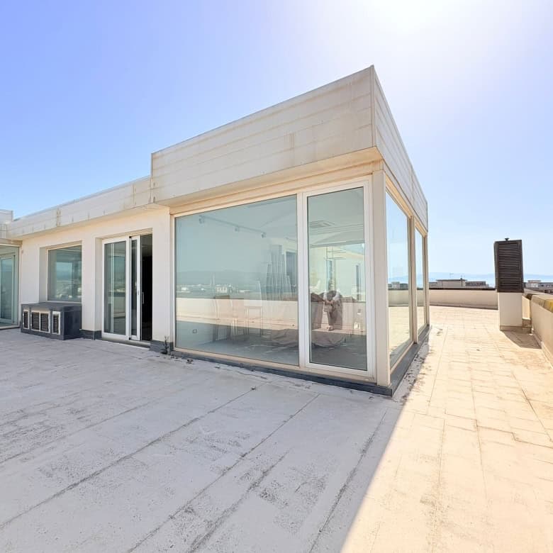 Balcone panoramico con vista sul mare, spazio esterno di un appartamento moderno in centro città, ideale per relax e convivialità, con ampie vetrate e arredi minimalisti.